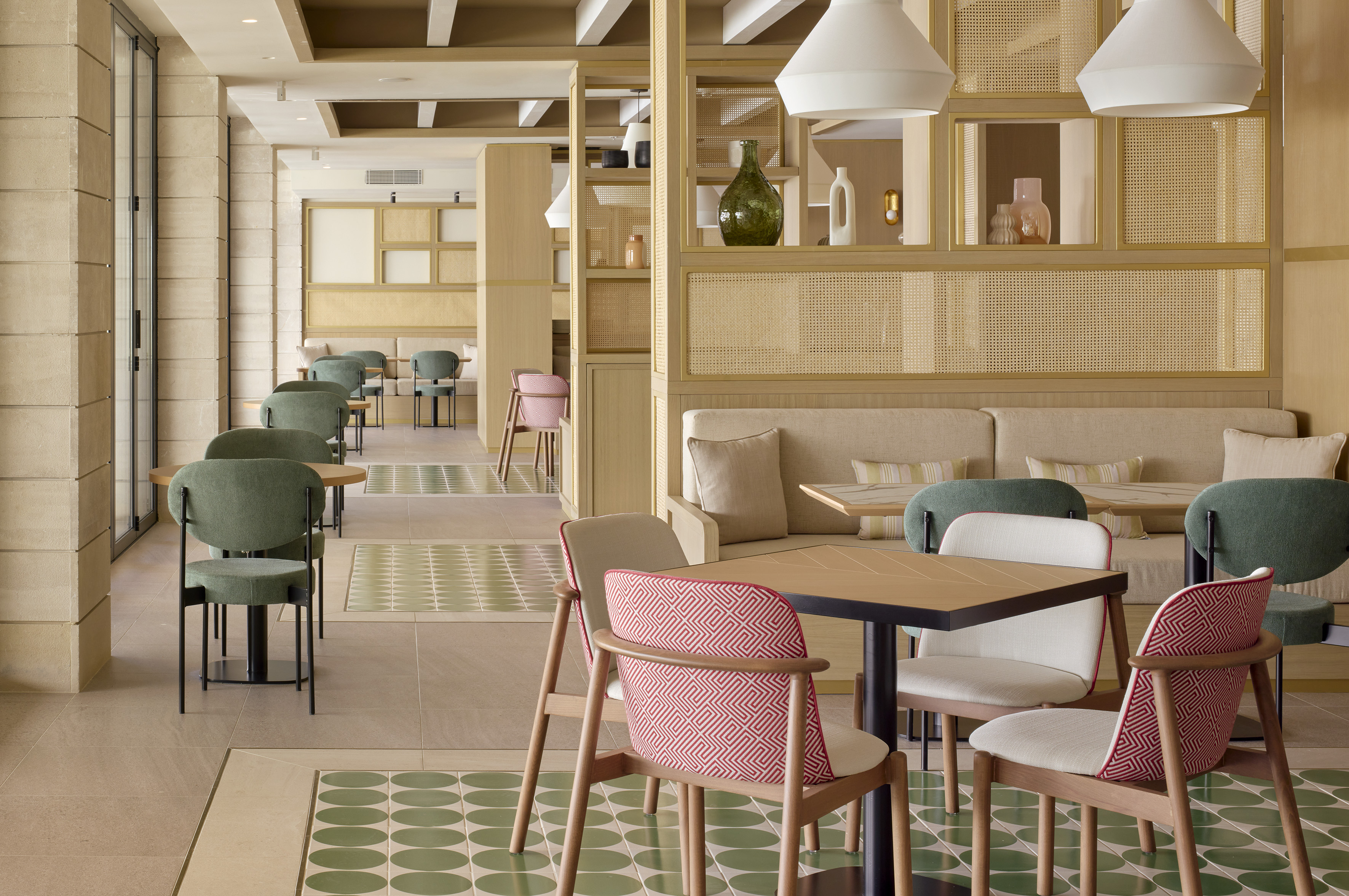 Contemporary cafe interior with green chairs, cane details, and geometric floor.