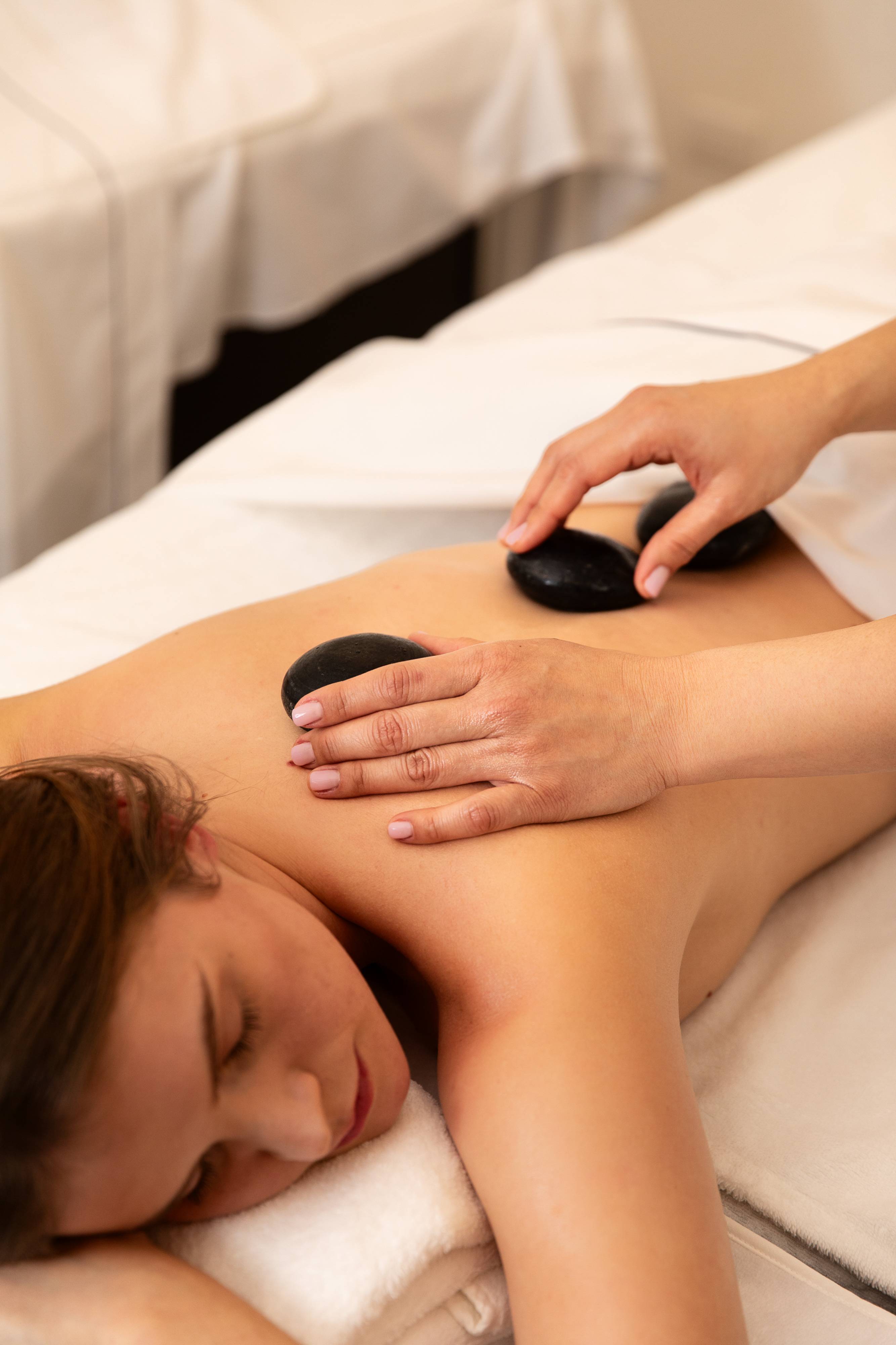 Spa hot stone massage on a woman's back for relaxation.