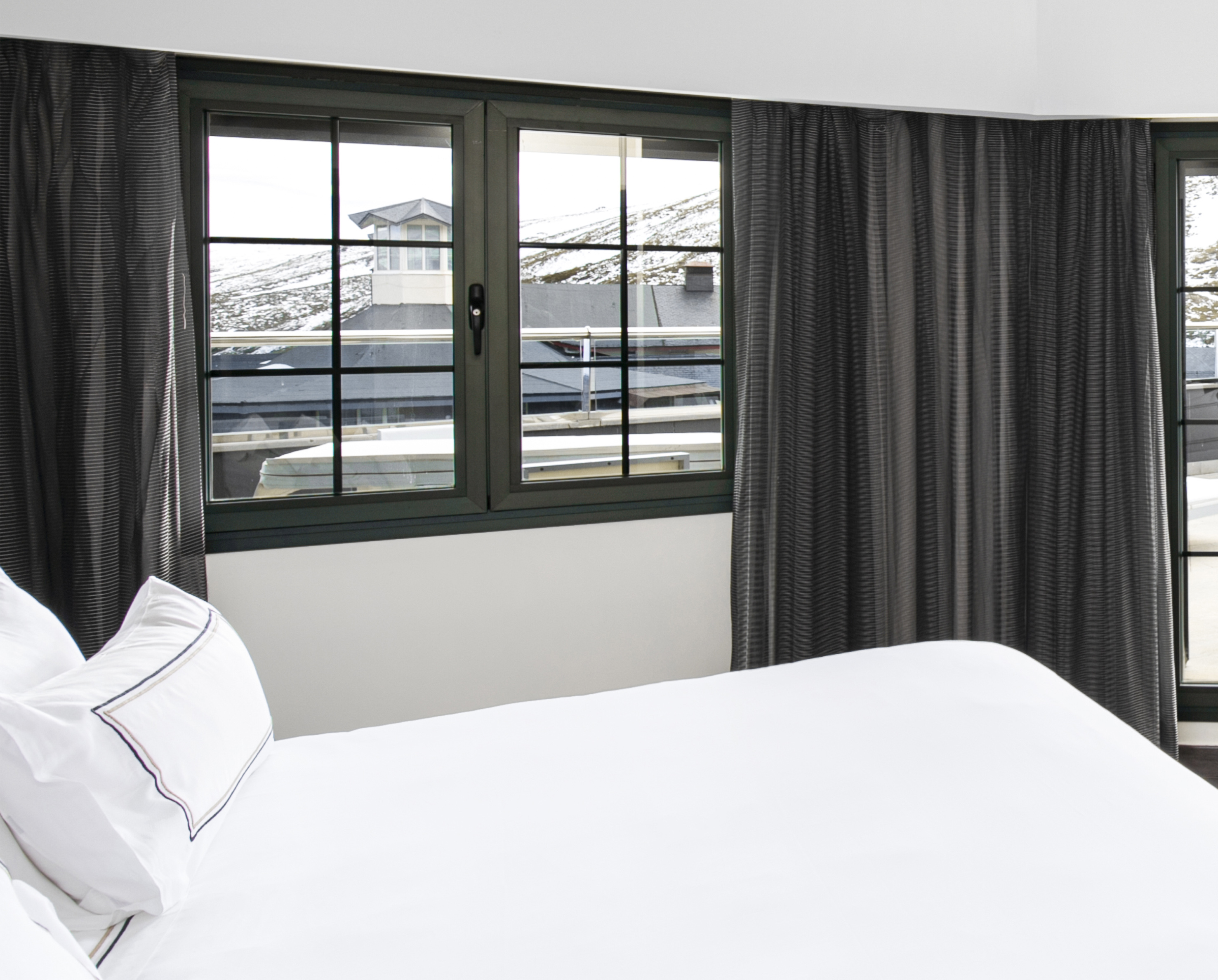a bed with white sheets and black curtains