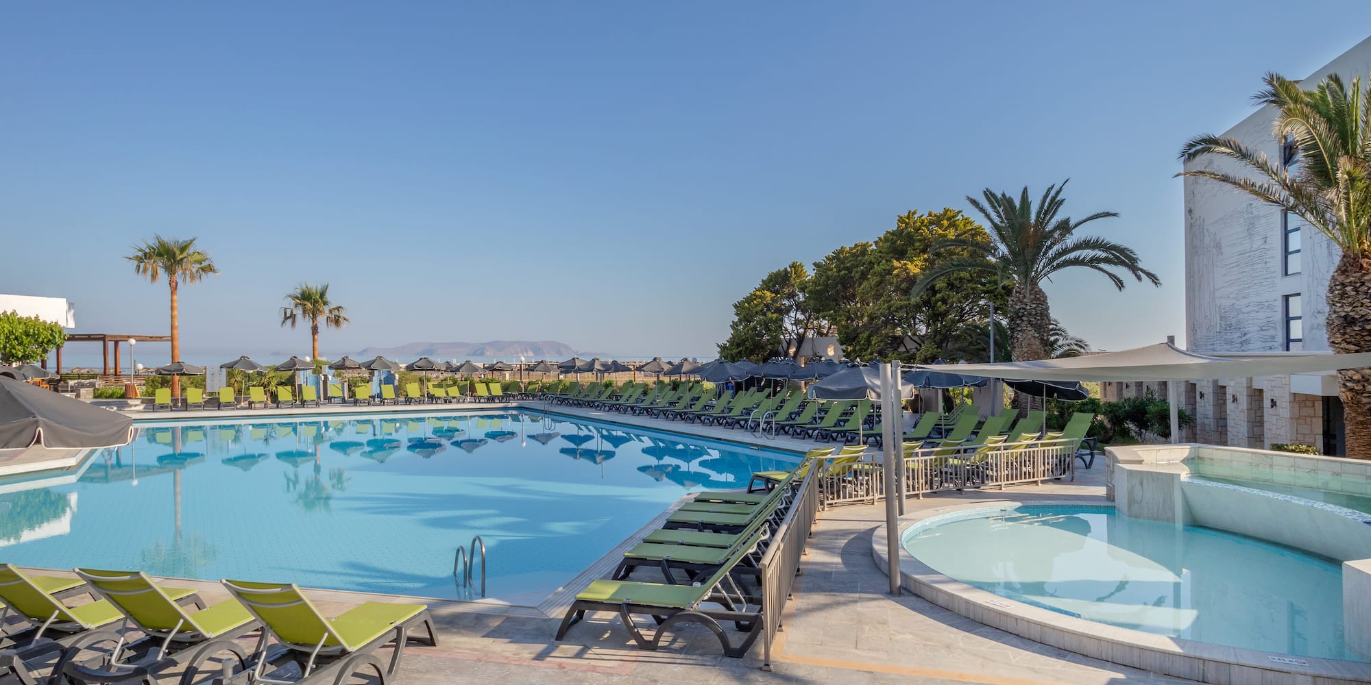 a pool with lounge chairs and a hot tub