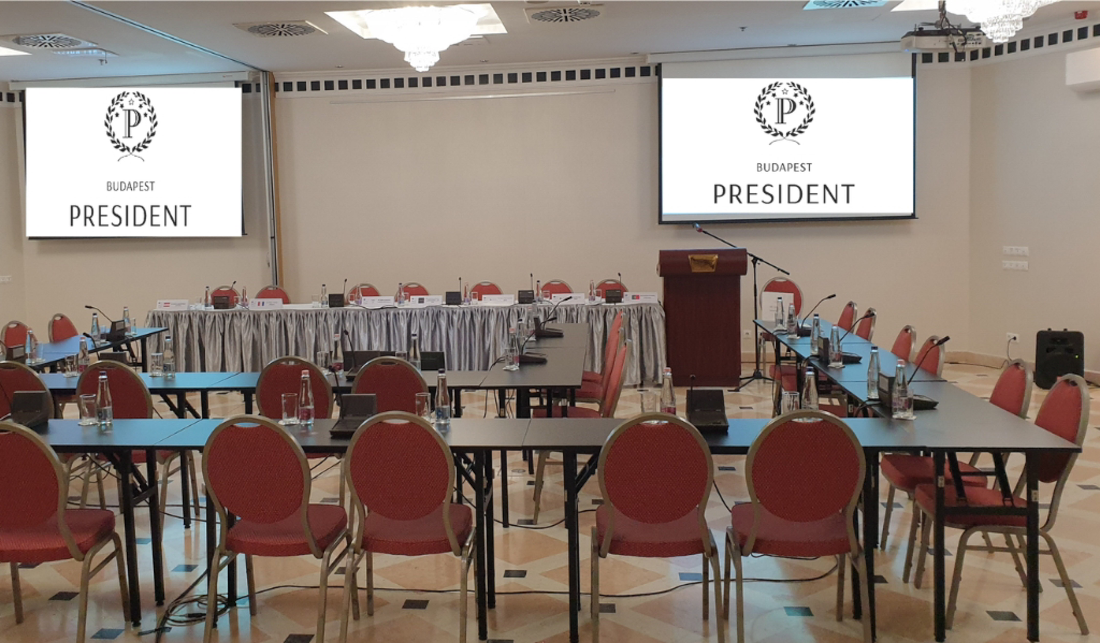 Budapest conference room with tables, red chairs, and President screens.