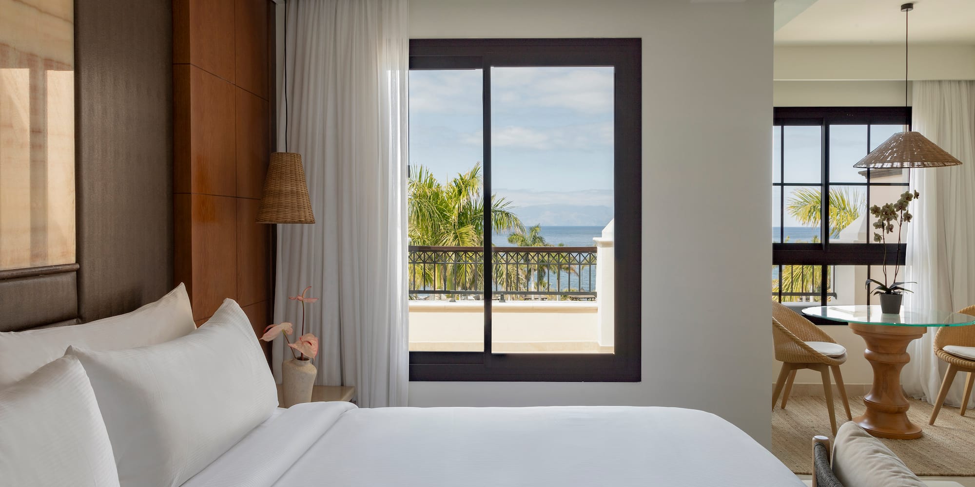 a bed with white sheets and a window overlooking a body of water