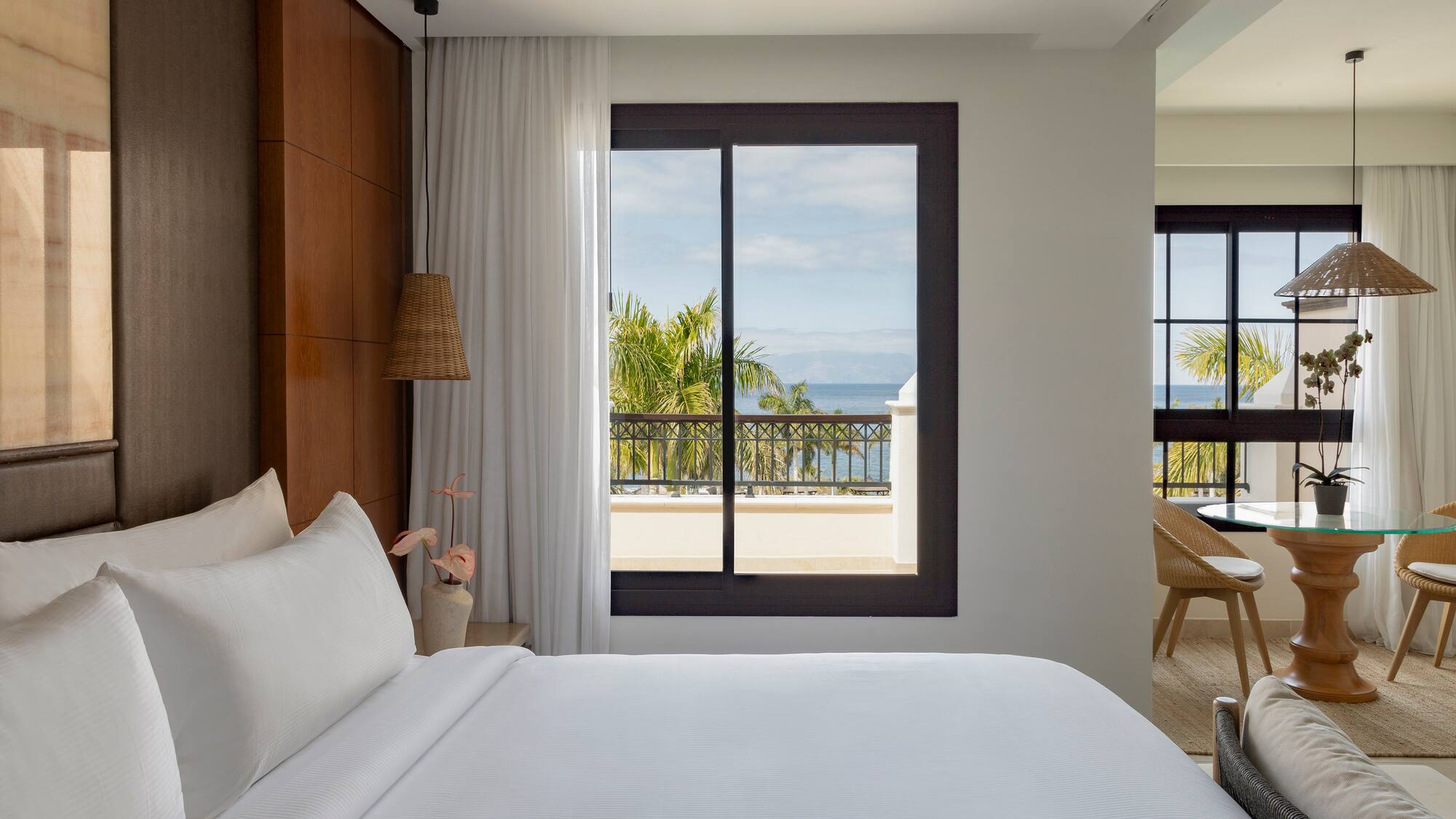 a bed with white sheets and a window overlooking a body of water