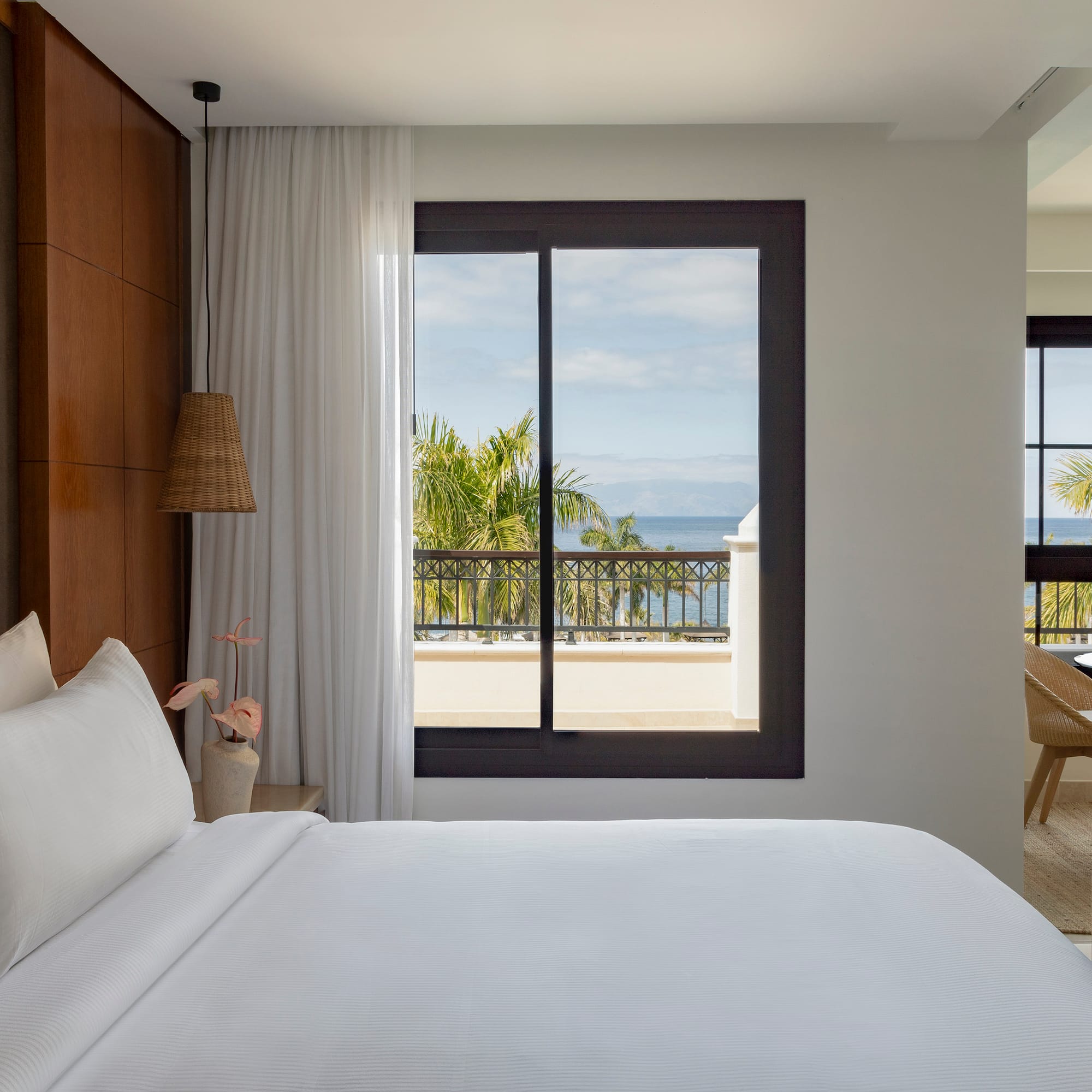 a bed with white sheets and a window overlooking a body of water