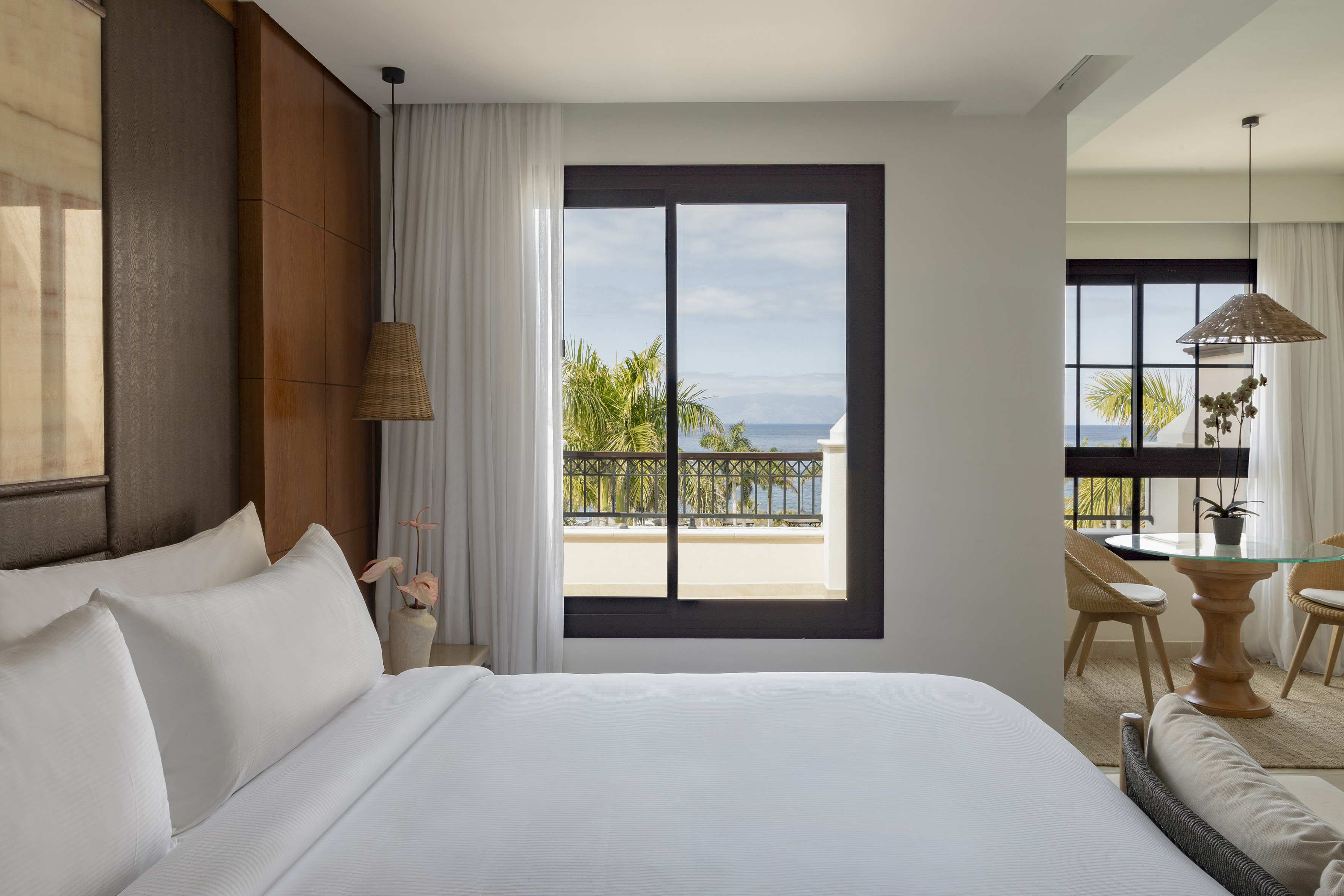 a bed with white sheets and a window overlooking a body of water