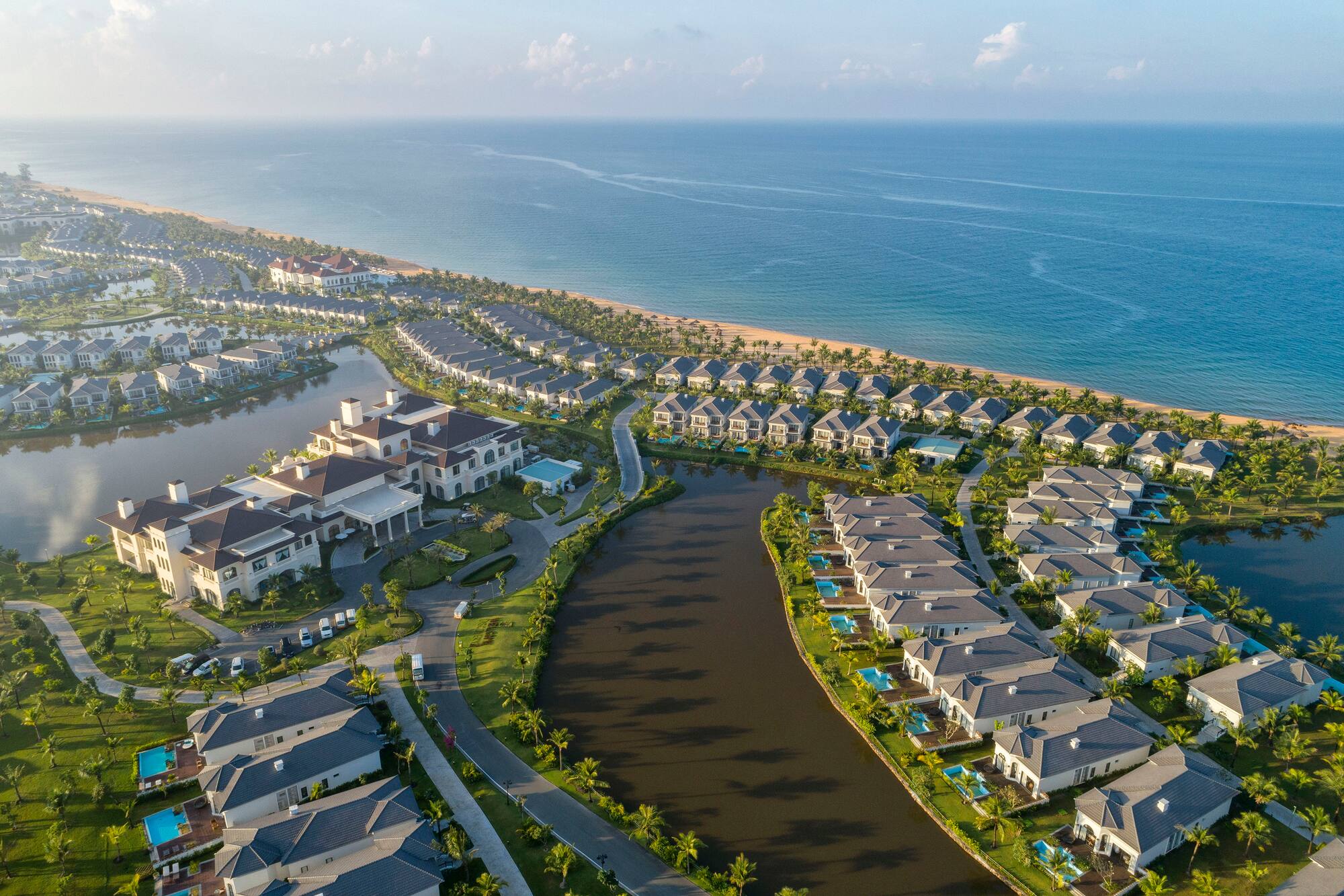 Aerial view: Oceanfront resort villas, canals, and lush tropical landscaping.