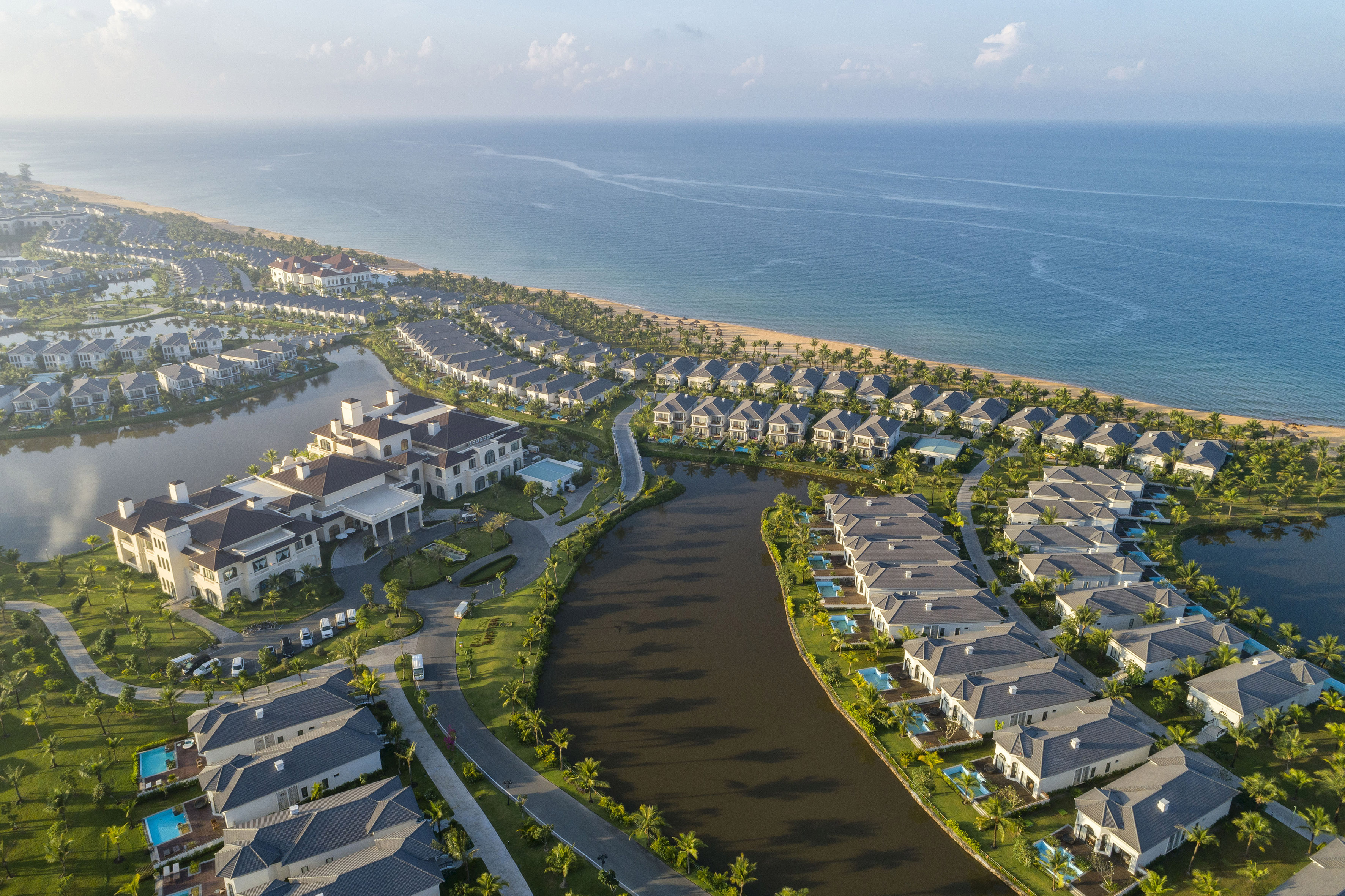 Aerial view: Oceanfront resort villas, canals, and lush tropical landscaping.