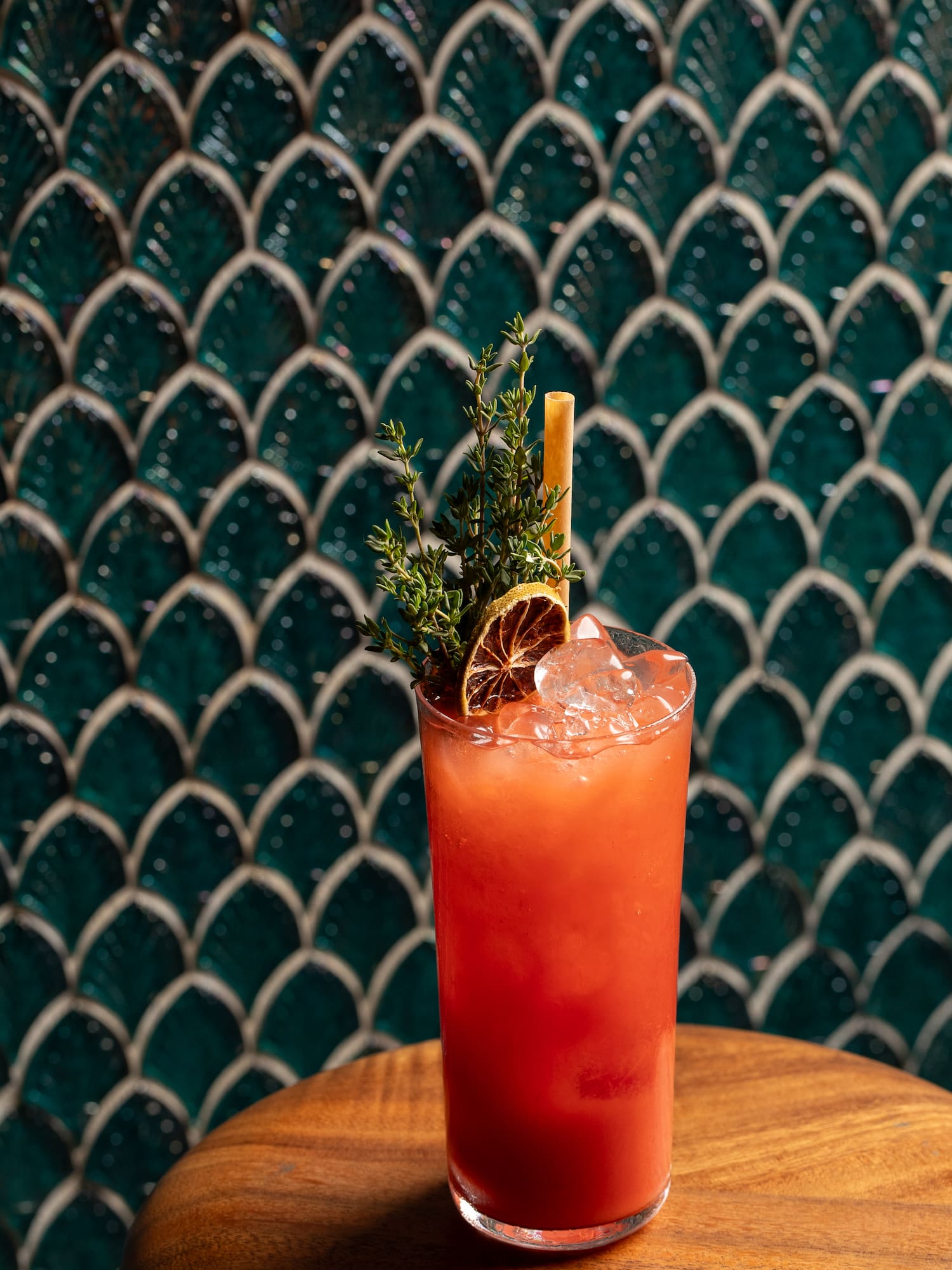 a glass of red liquid with a slice of orange and a branch on top of it