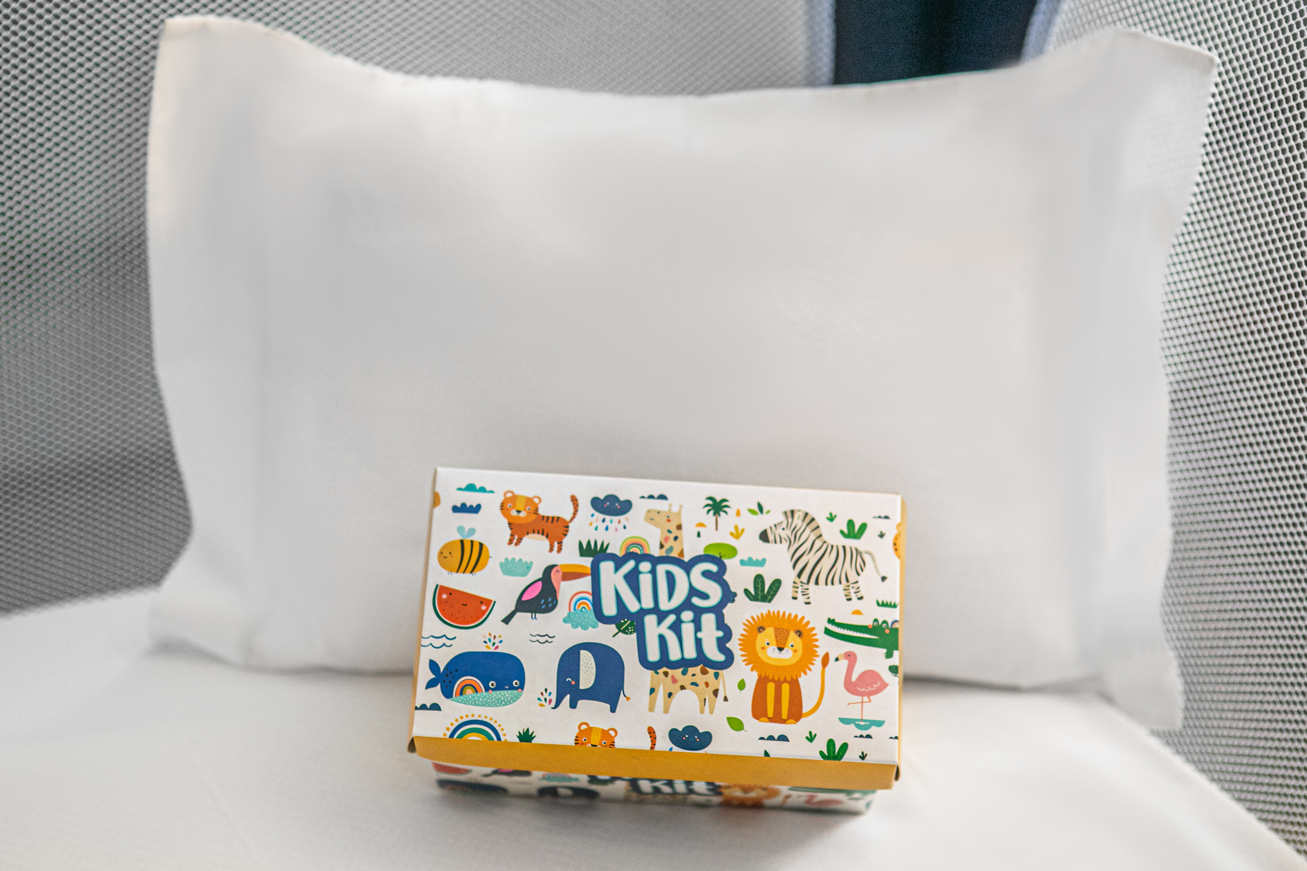 Colorful Kids Kit box with vibrant animal designs on a white bed pillow.
