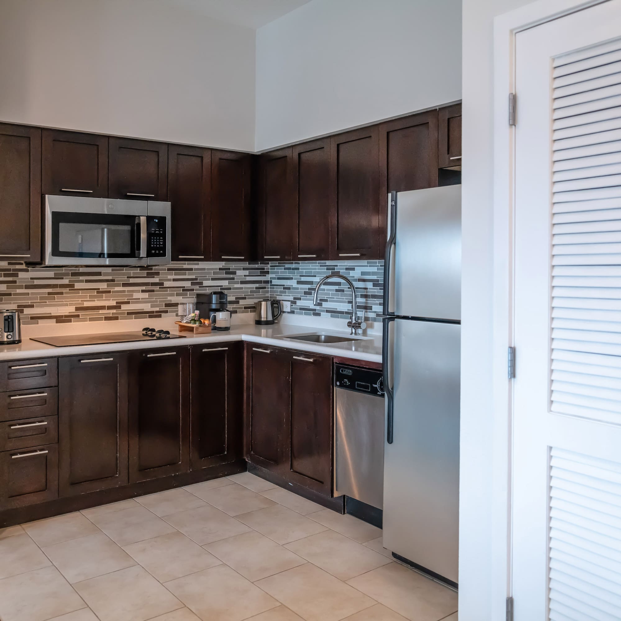 a kitchen with dark wood cabinets and a stainless steel refrigerator