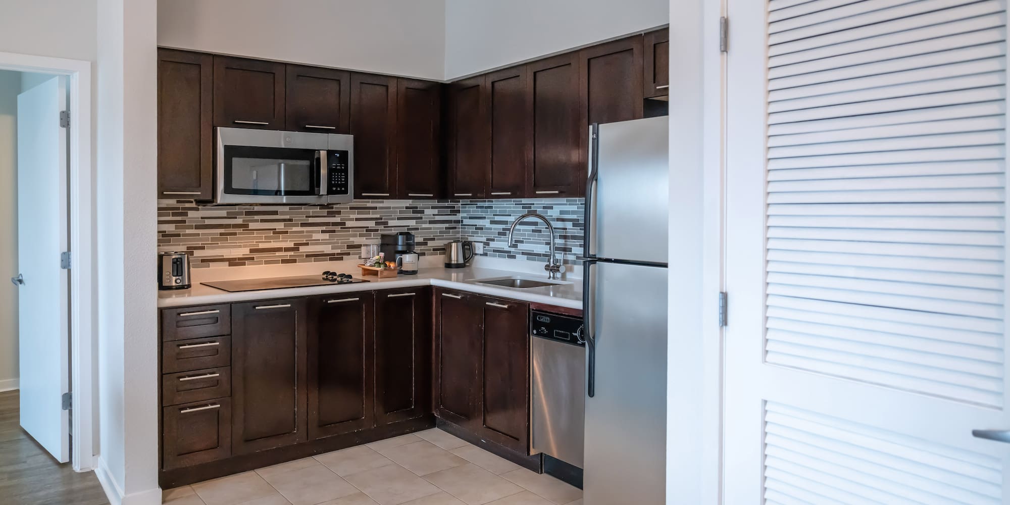 a kitchen with dark wood cabinets and a stainless steel refrigerator