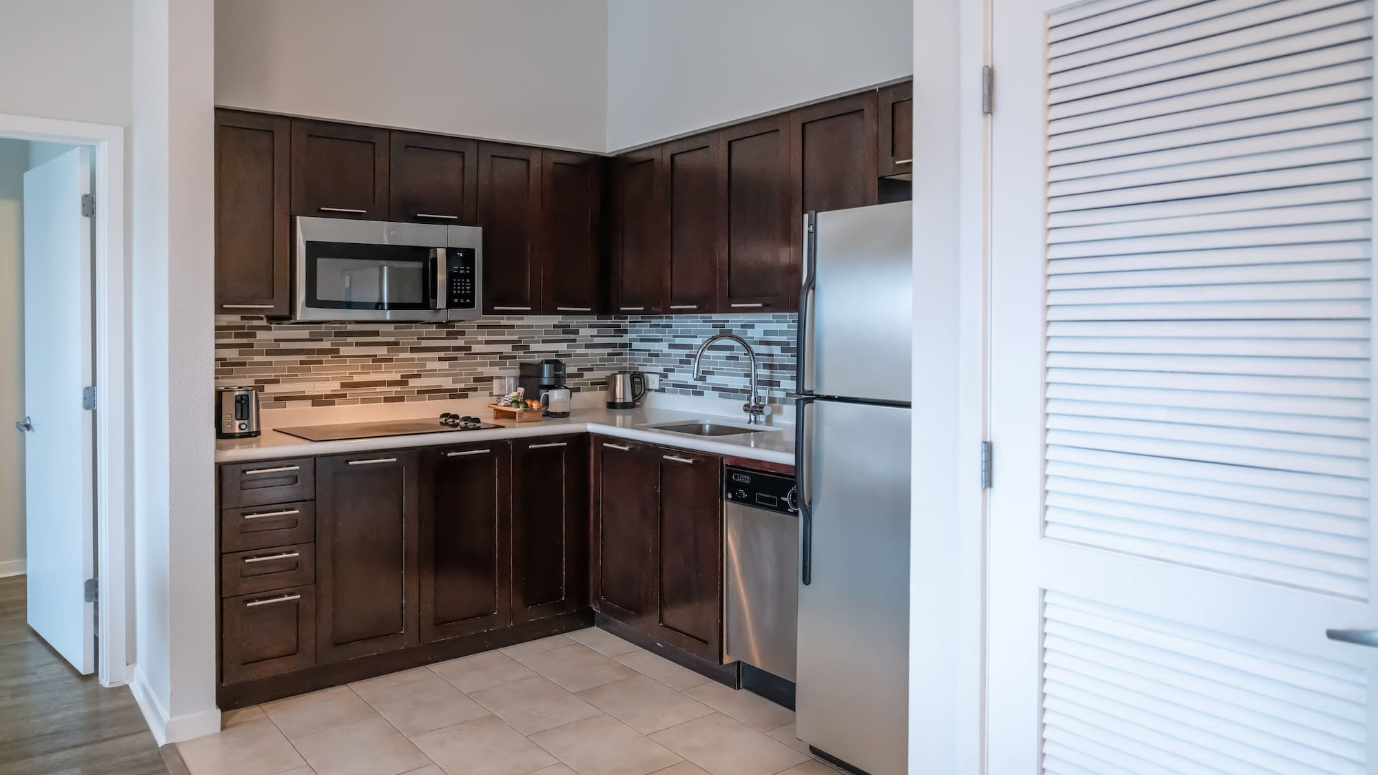 a kitchen with dark wood cabinets and a stainless steel refrigerator