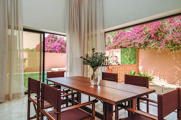 a table with chairs and a vase of flowers in front of a window