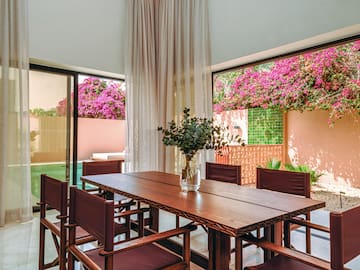 a table with chairs and a vase of flowers in front of a window