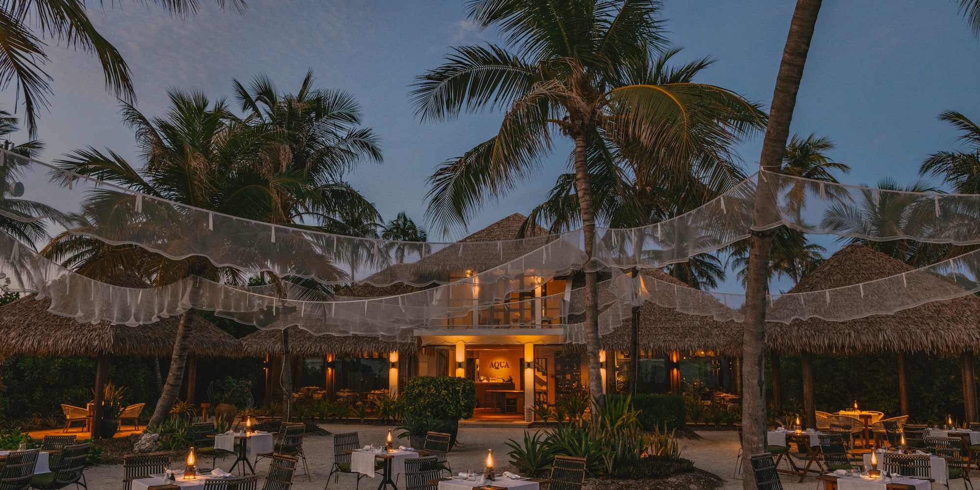 a restaurant with tables and chairs in the middle of a beach