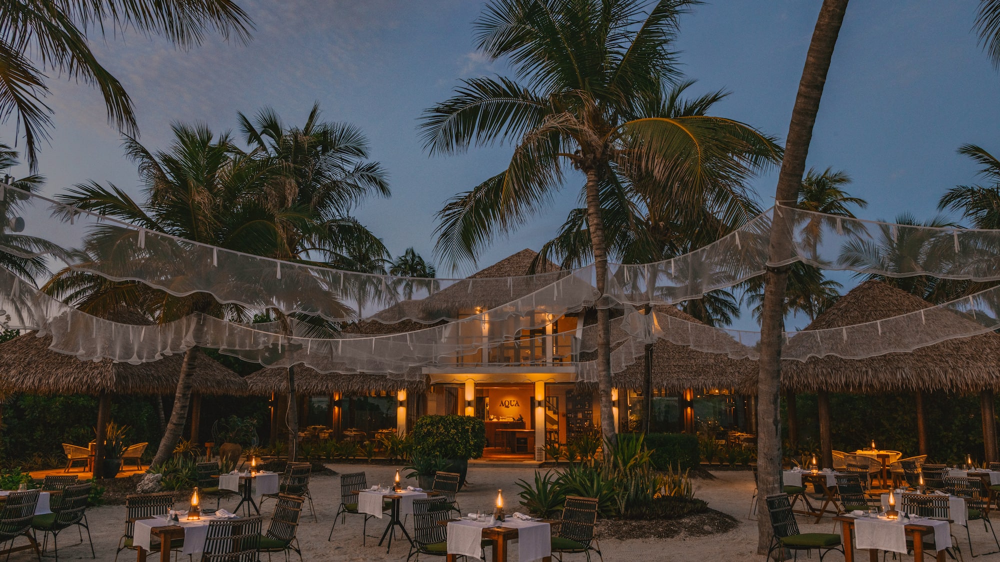 a restaurant with tables and chairs in the middle of a beach