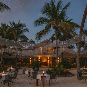 a restaurant with tables and chairs in the middle of a beach