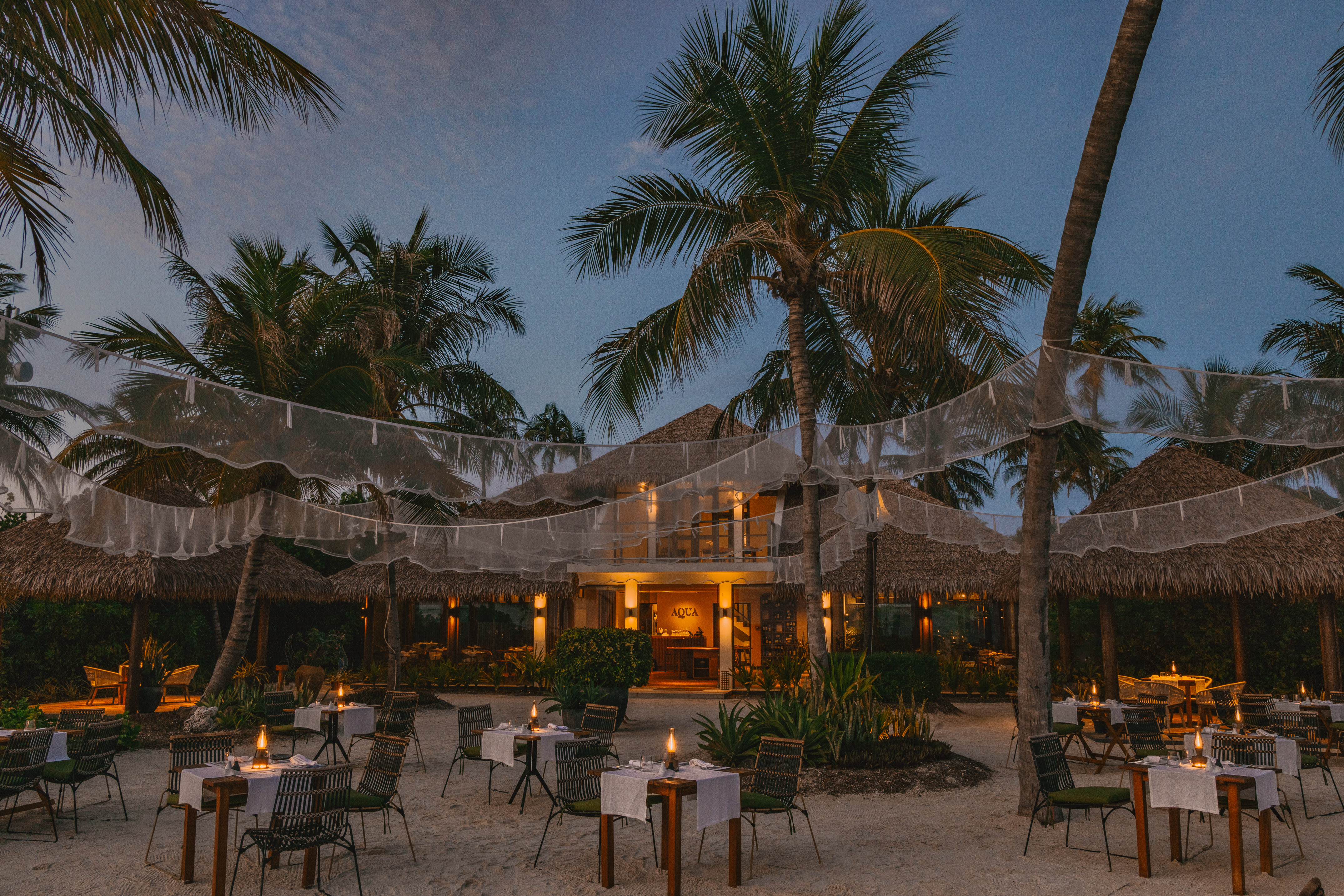 a restaurant with tables and chairs in the middle of a beach