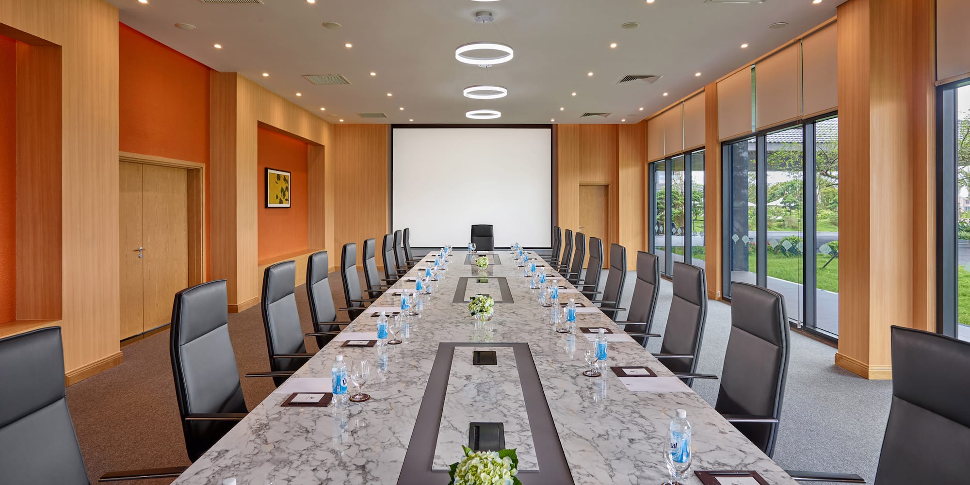 a conference room with a large table with chairs and a projector screen