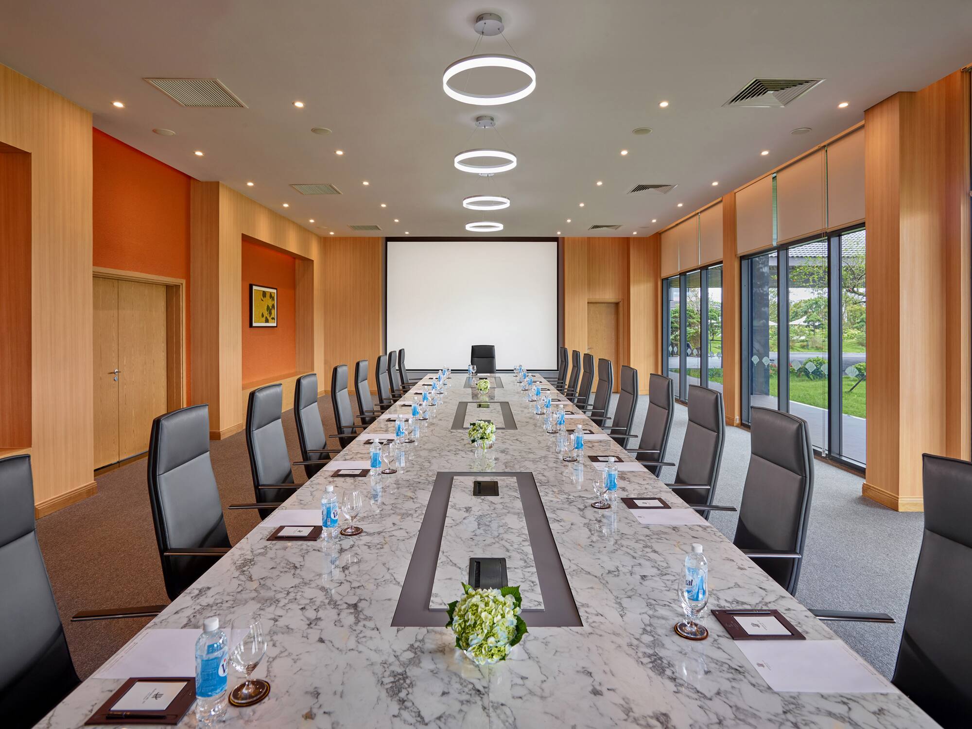 a conference room with a large table with chairs and a projector screen