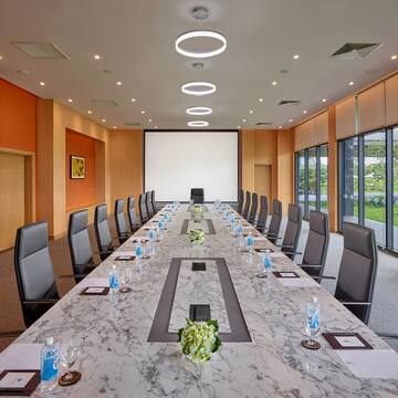 a conference room with a large table with chairs and a projector screen