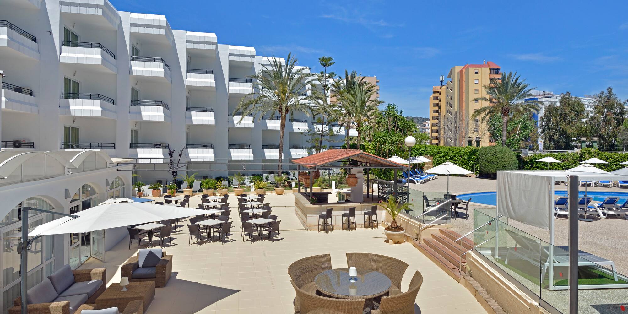 a patio with chairs and tables and a pool in the background
