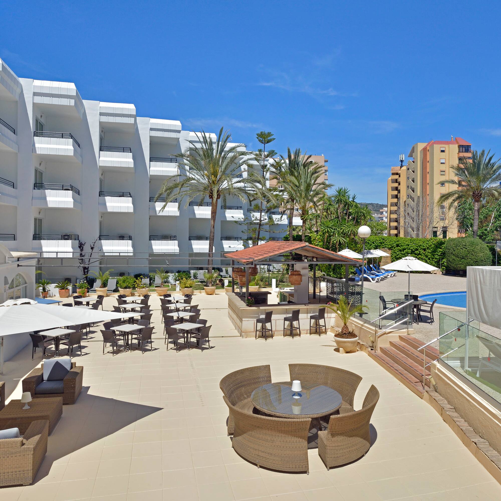 a patio with chairs and tables and a pool in the background