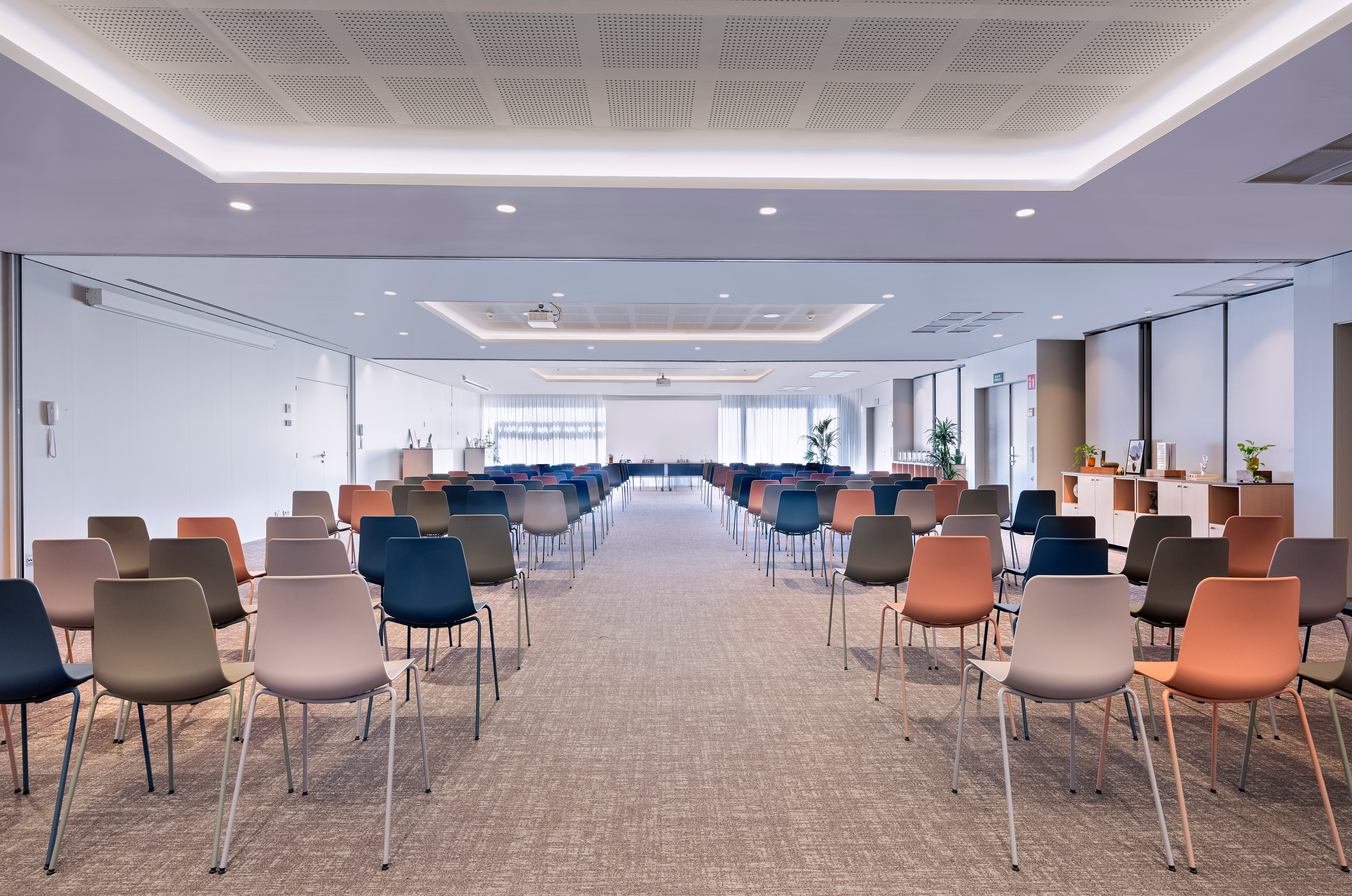 Empty modern conference room with colorful chairs, projector, and large screen.