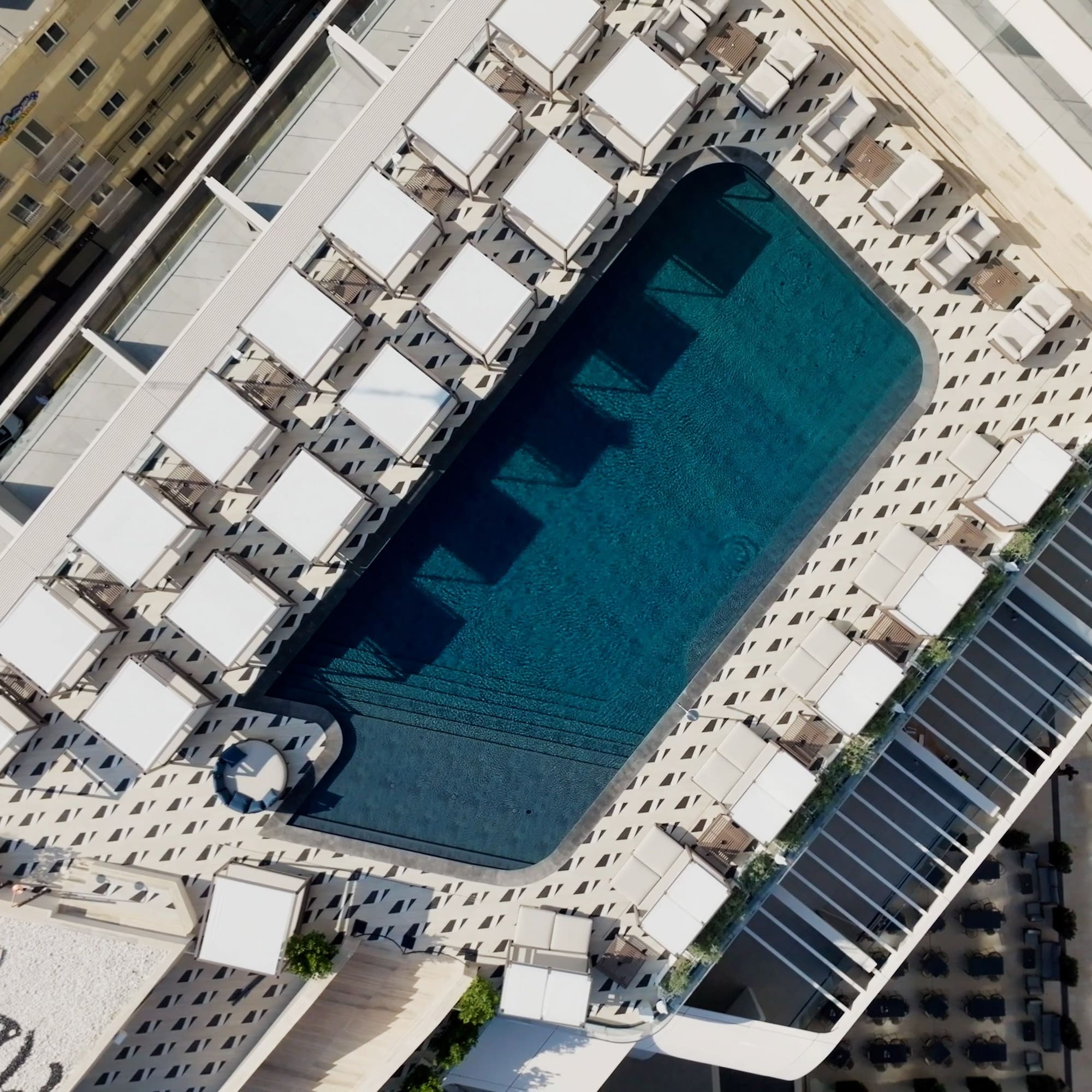 a pool with white umbrellas and tables on top of a building