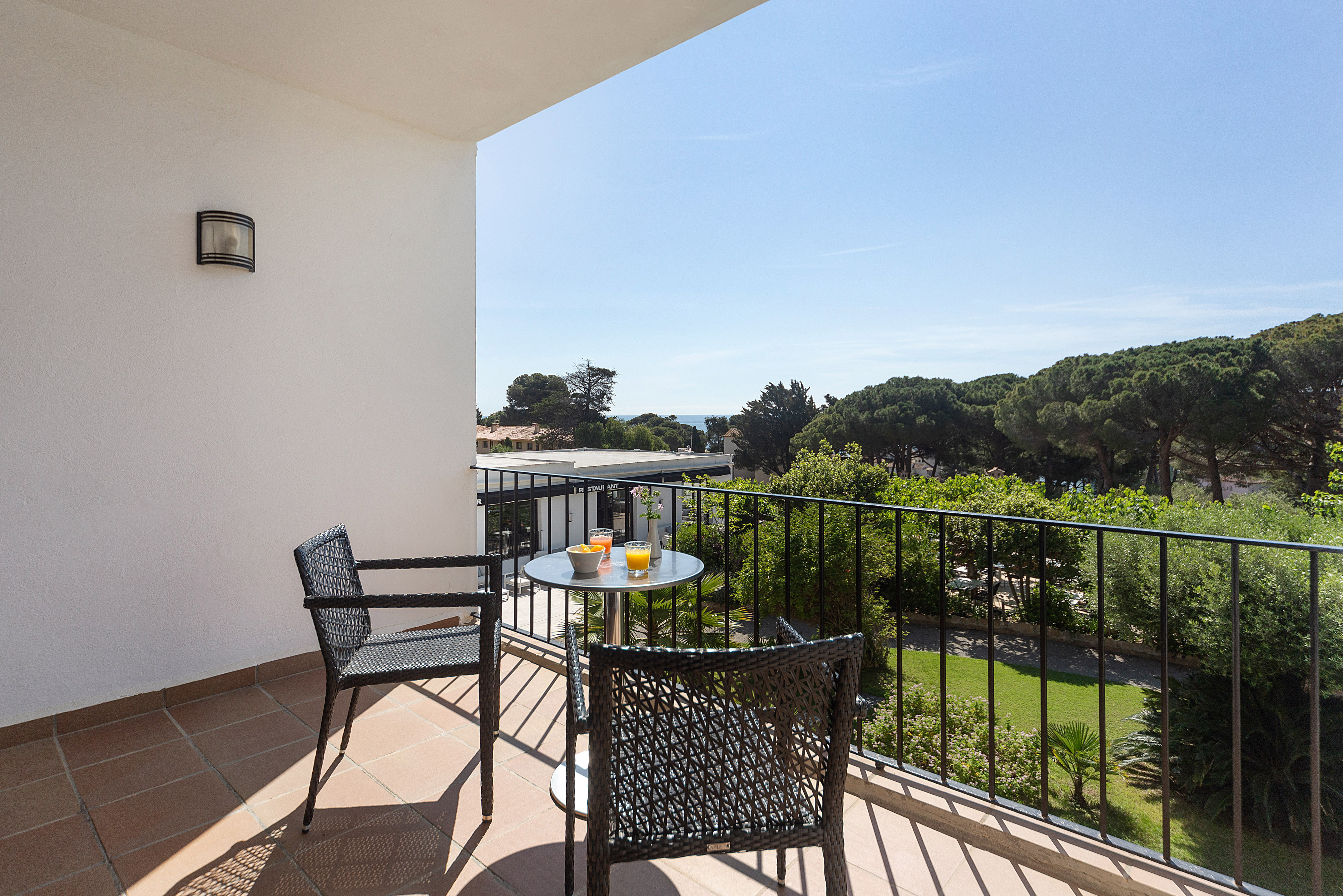 Sunny balcony with outdoor seating, juice, fruit, sea and pine forest view.
