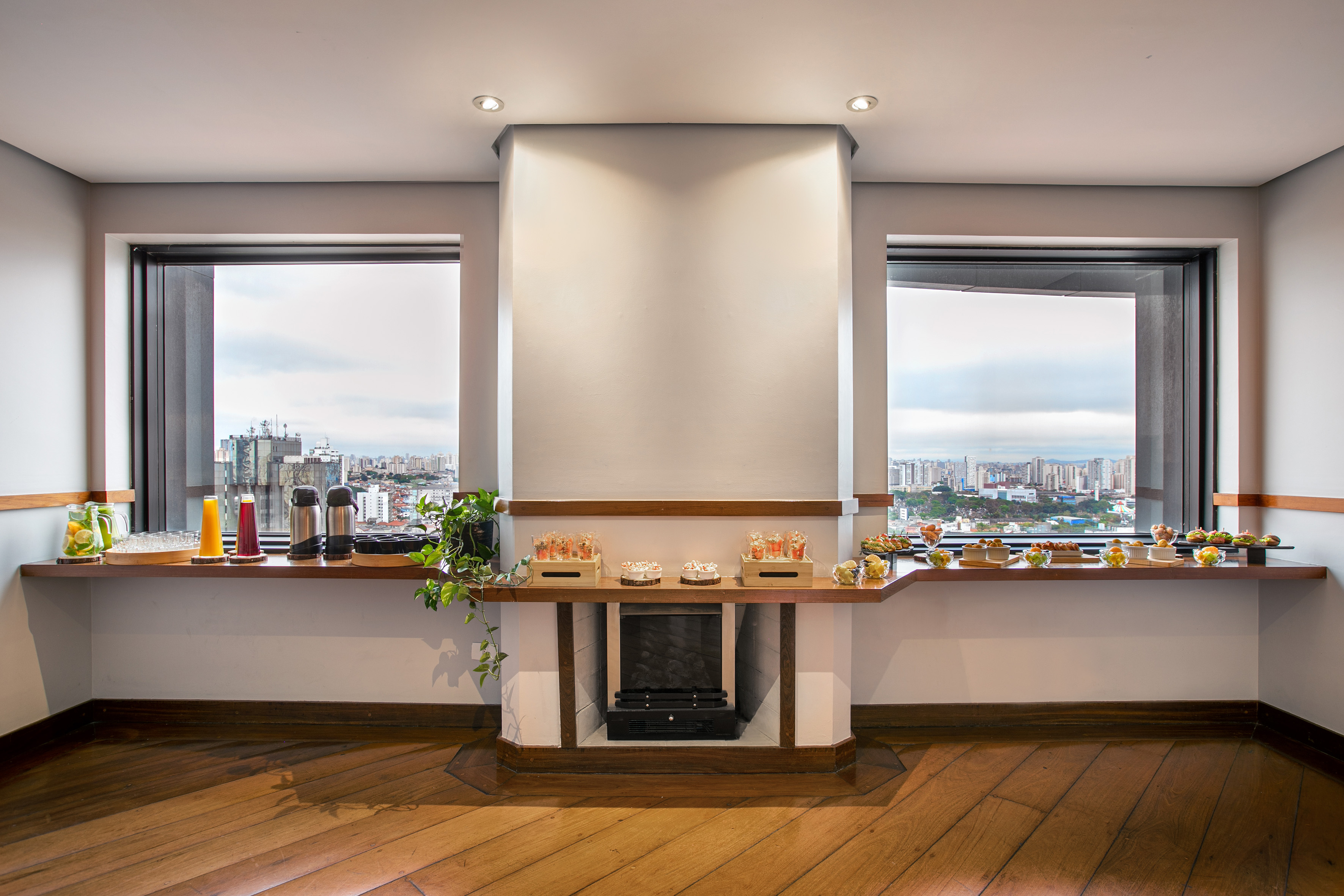 Buffet catering setup in modern event room with city view and fireplace.