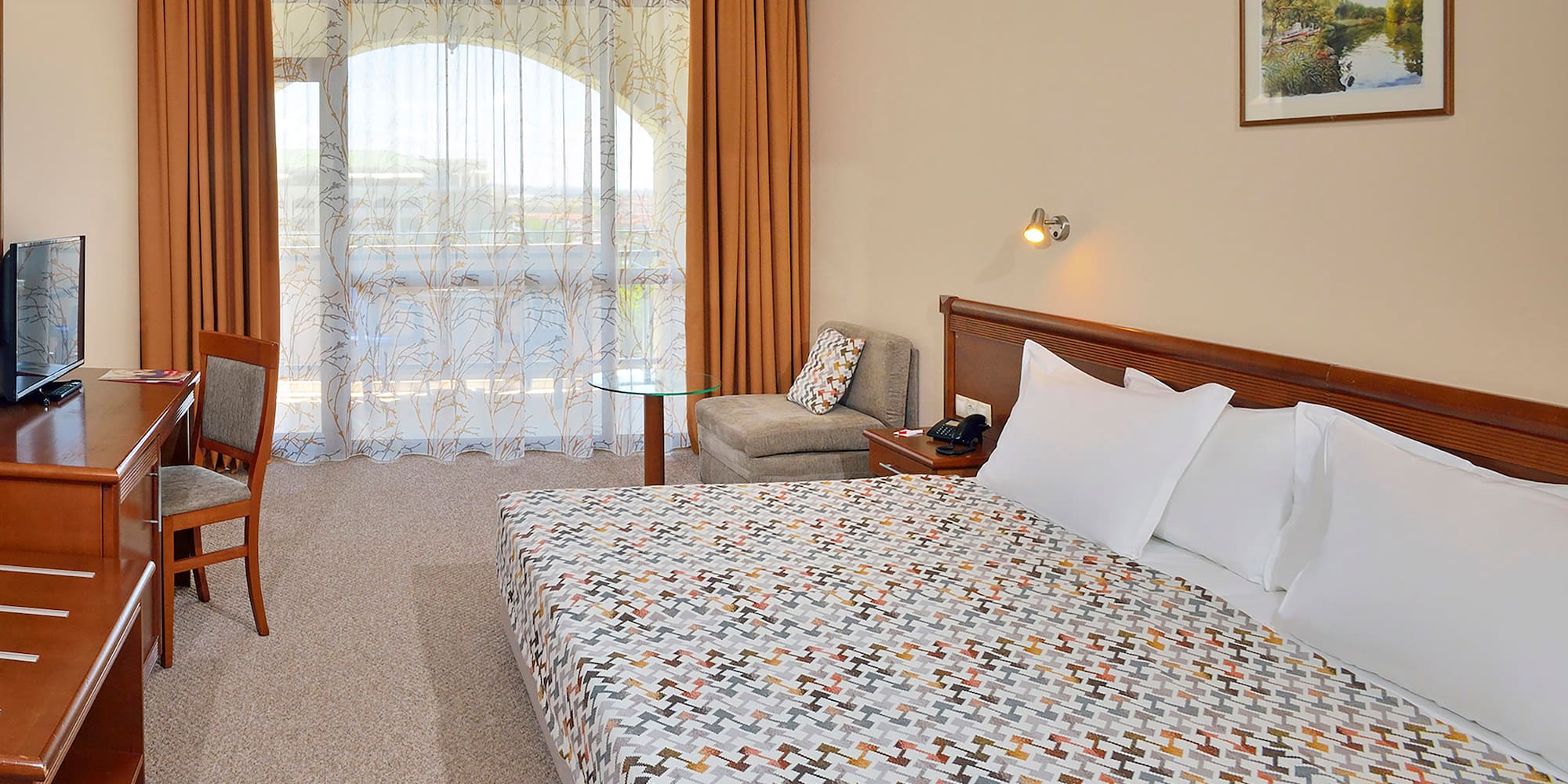 a bed with a patterned blanket and a chair in a hotel room