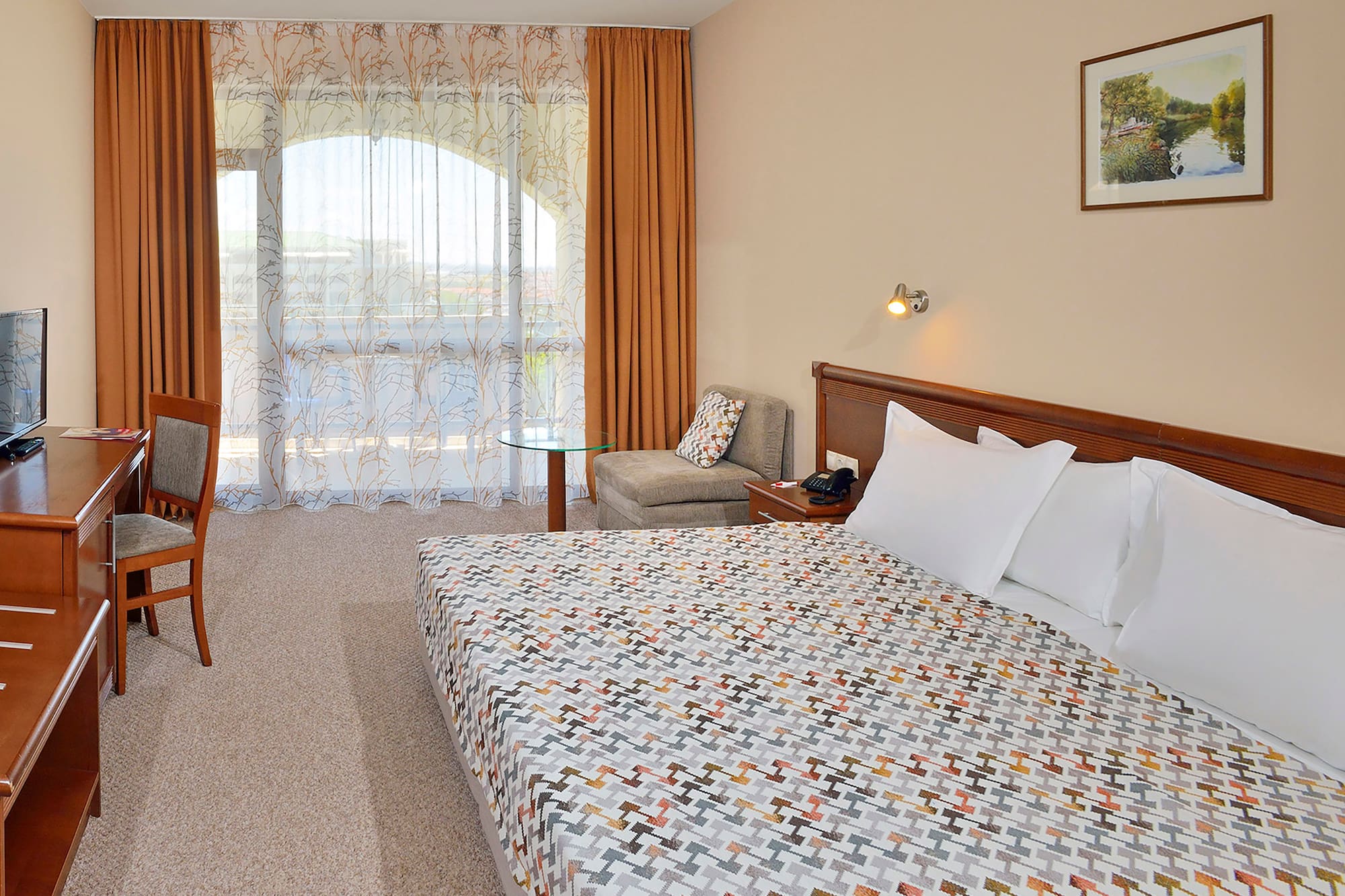a bed with a patterned blanket and a chair in a hotel room