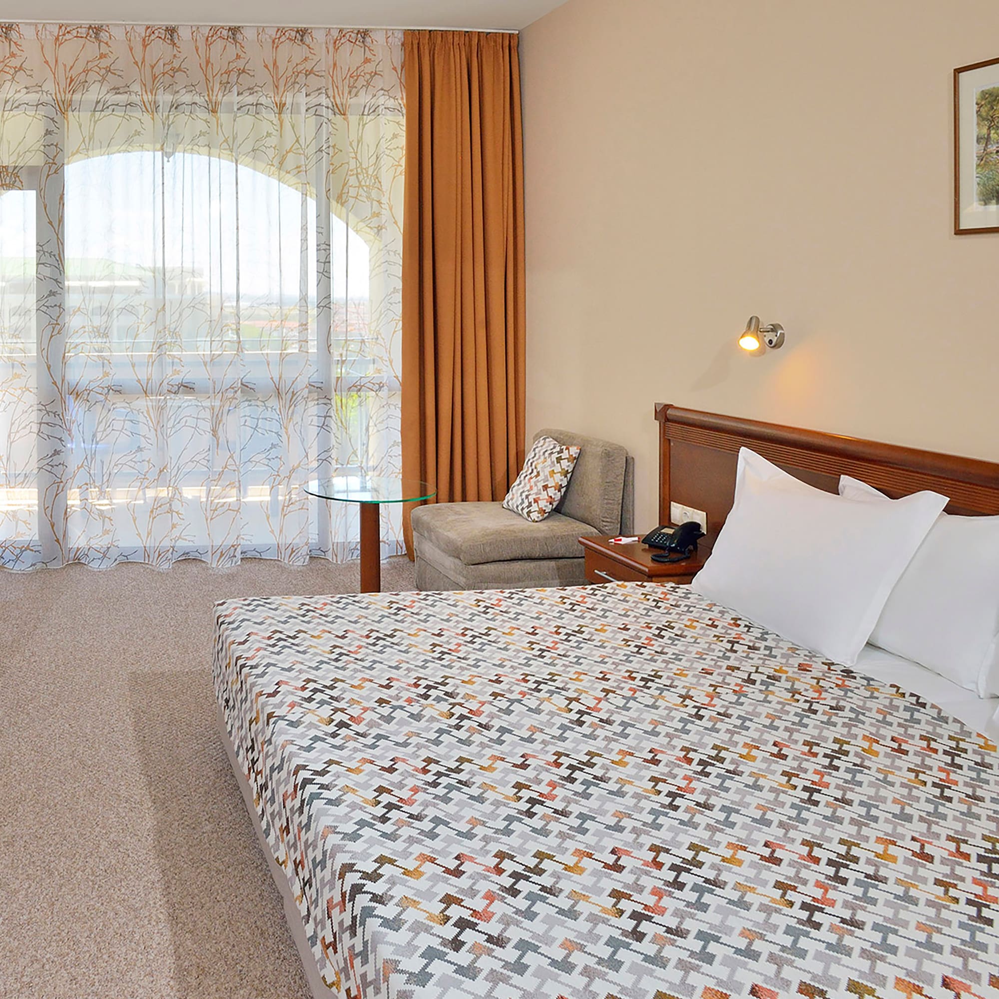 a bed with a patterned blanket and a chair in a hotel room