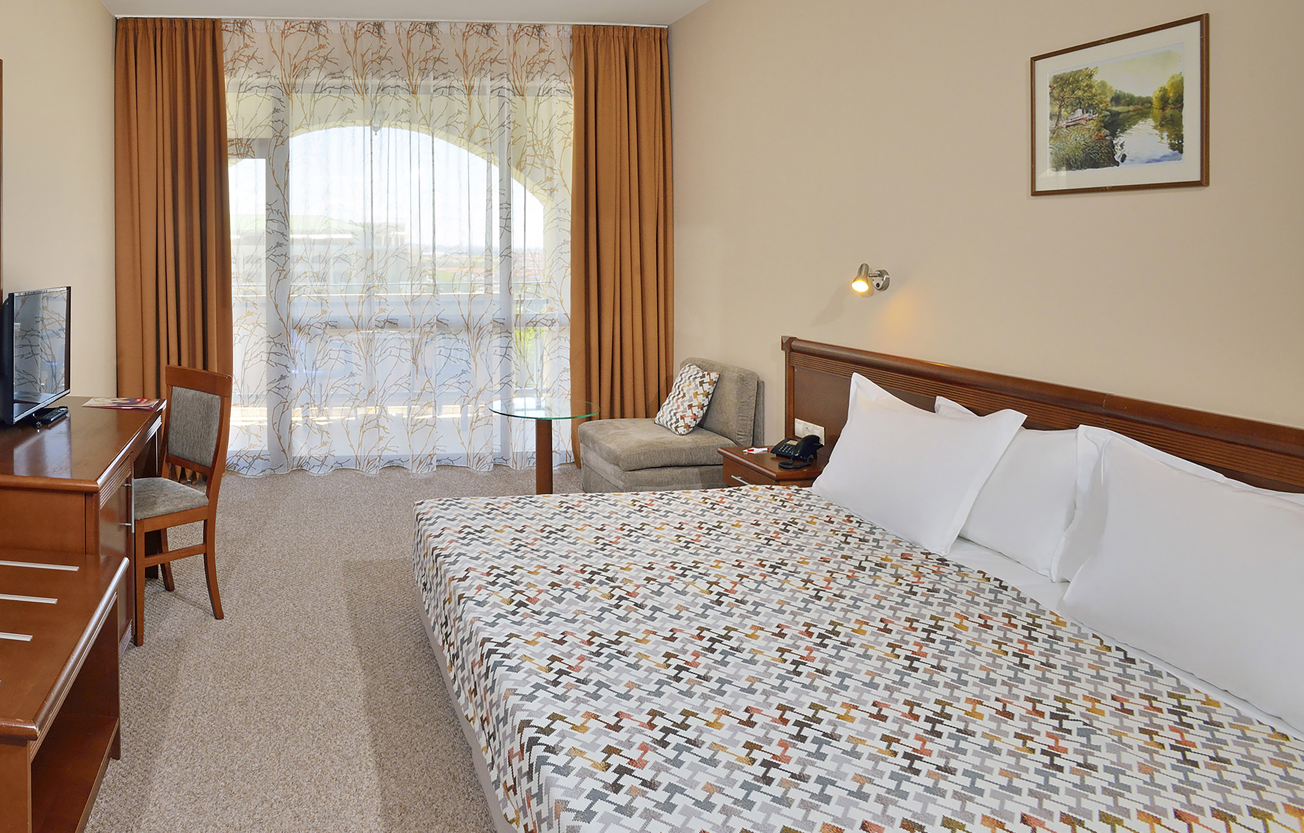 a bed with a patterned blanket and a chair in a hotel room