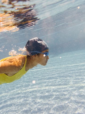 a woman swimming underwater in a pool