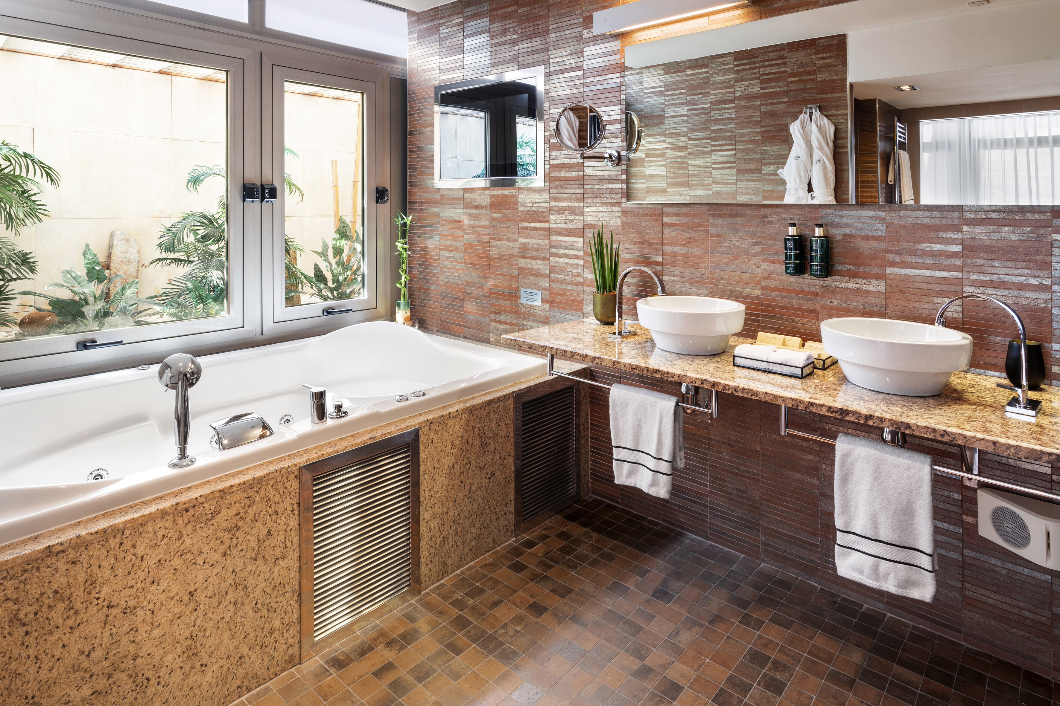 Luxury bathroom with jetted tub, double vanity, tiled walls, and garden window.