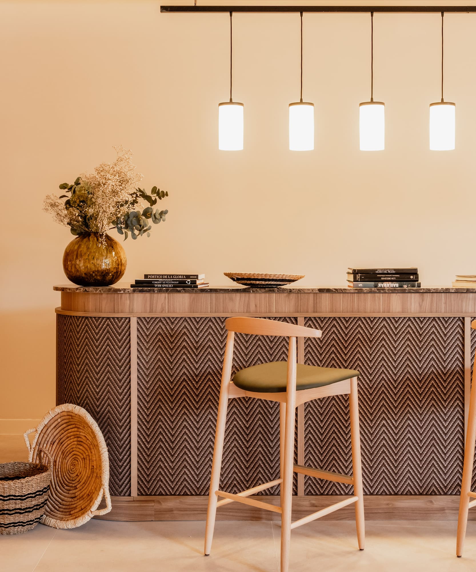 Modern bar counter, zigzag detail, wooden stools, pendant lights.