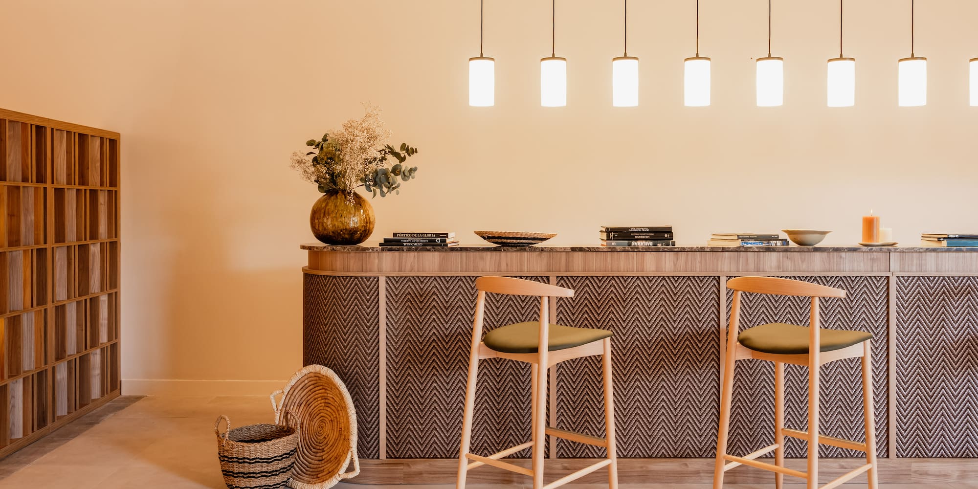 Modern interior with zigzag bar counter, wooden stools, and pendant lights.