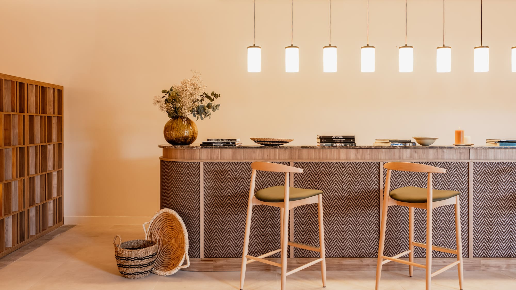Modern interior with zigzag bar counter, wooden stools, and pendant lights.