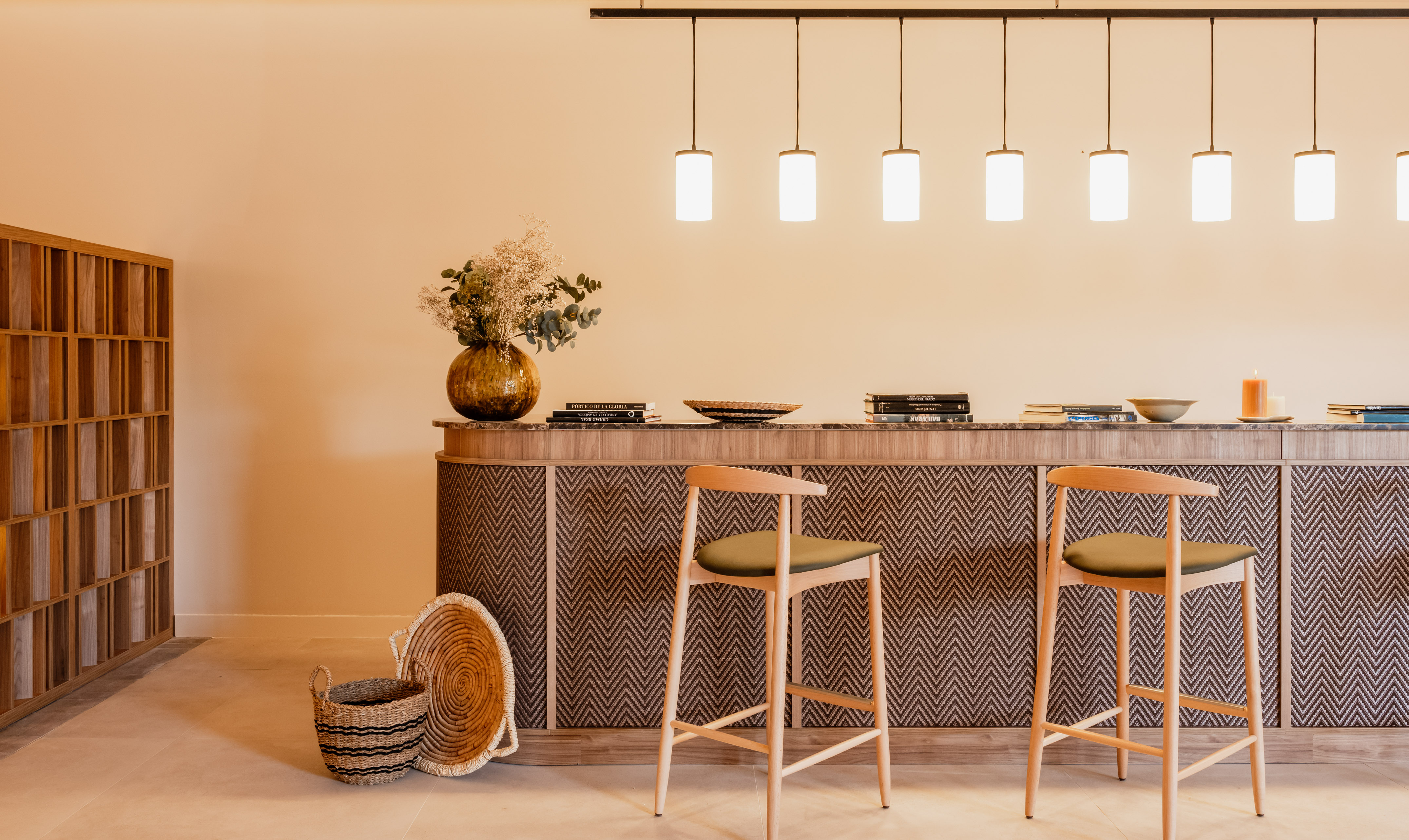 Modern bar counter, zigzag detail, wooden stools, pendant lights.