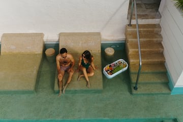 a man and woman sitting on a bench in a pool