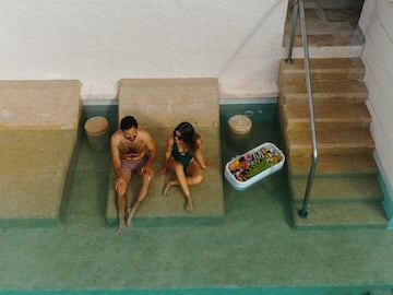 a man and woman sitting on a bench in a pool