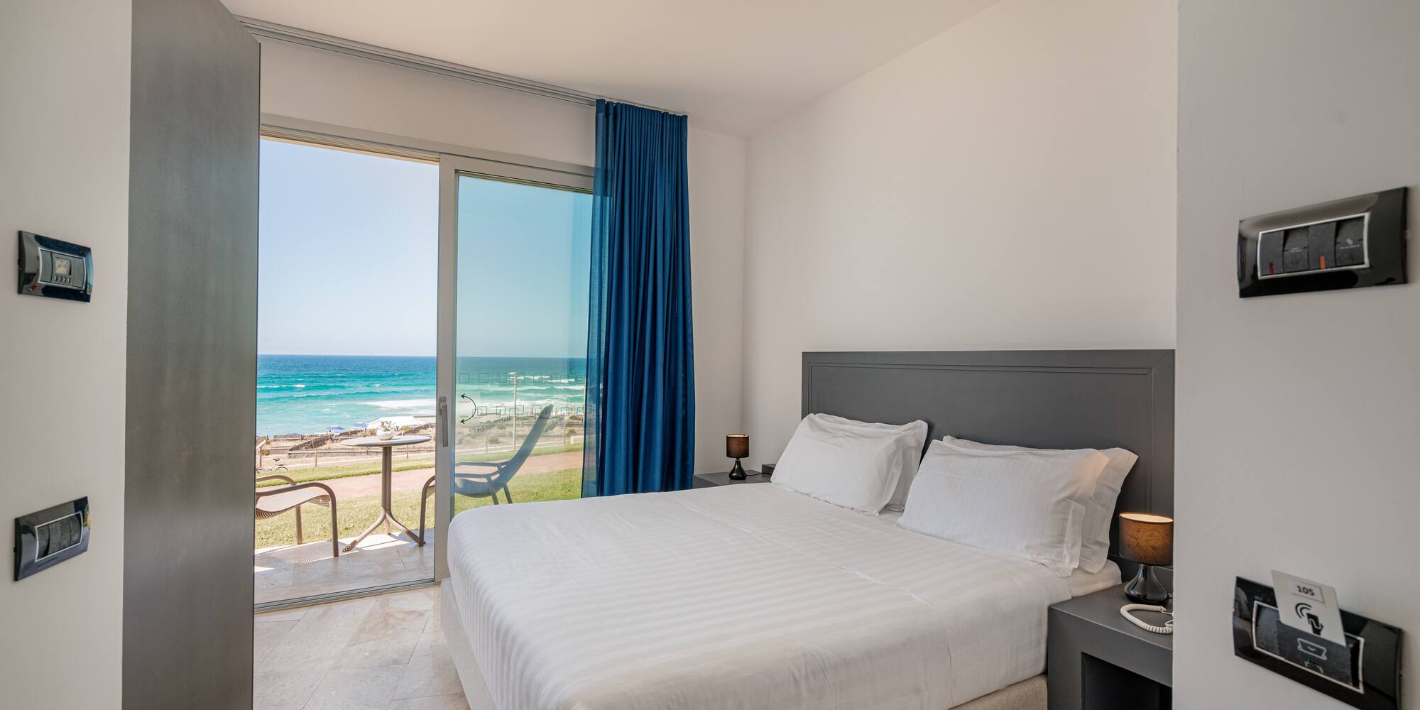 a bed with a glass door leading to the ocean