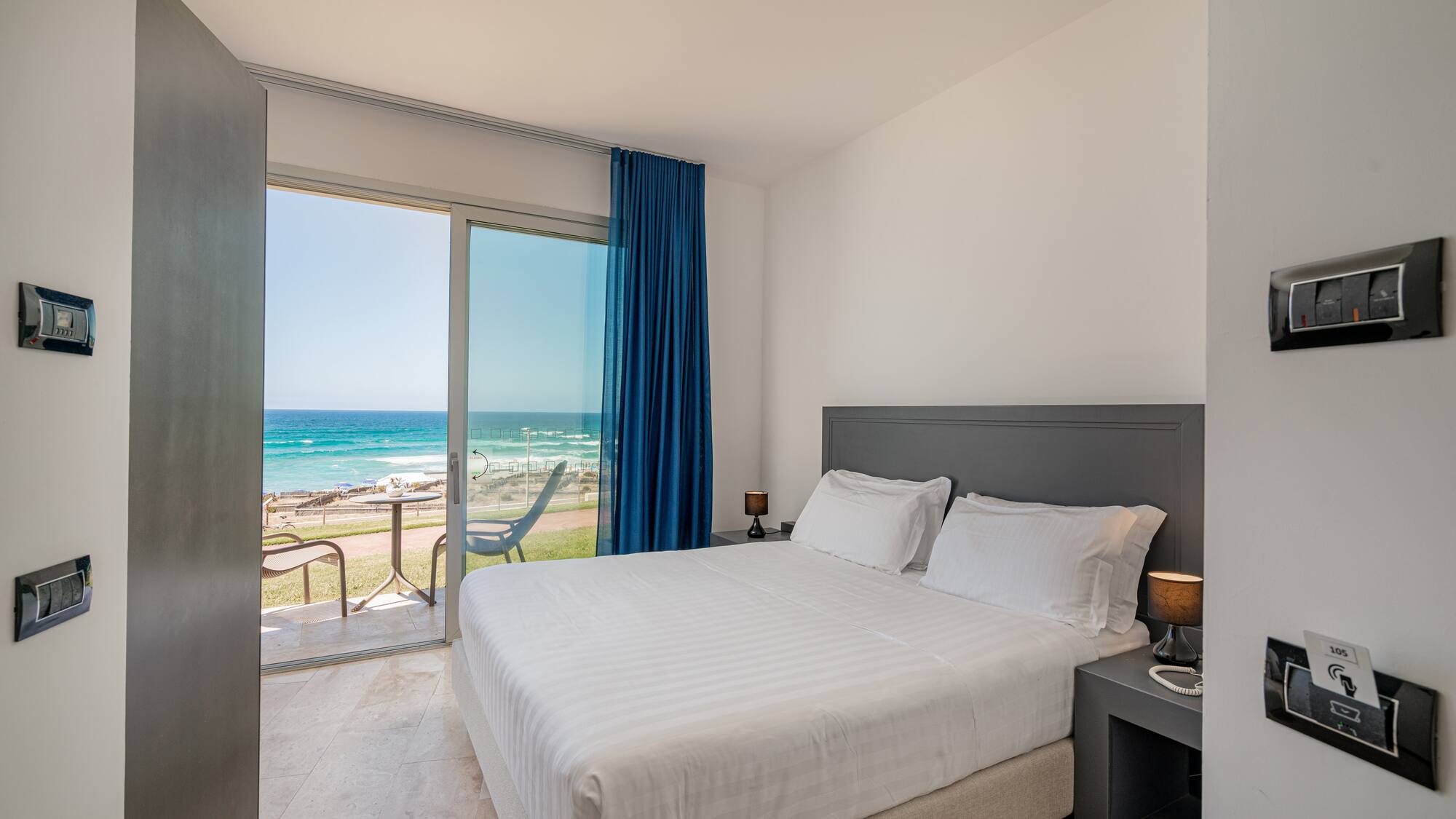 a bed with a glass door leading to the ocean
