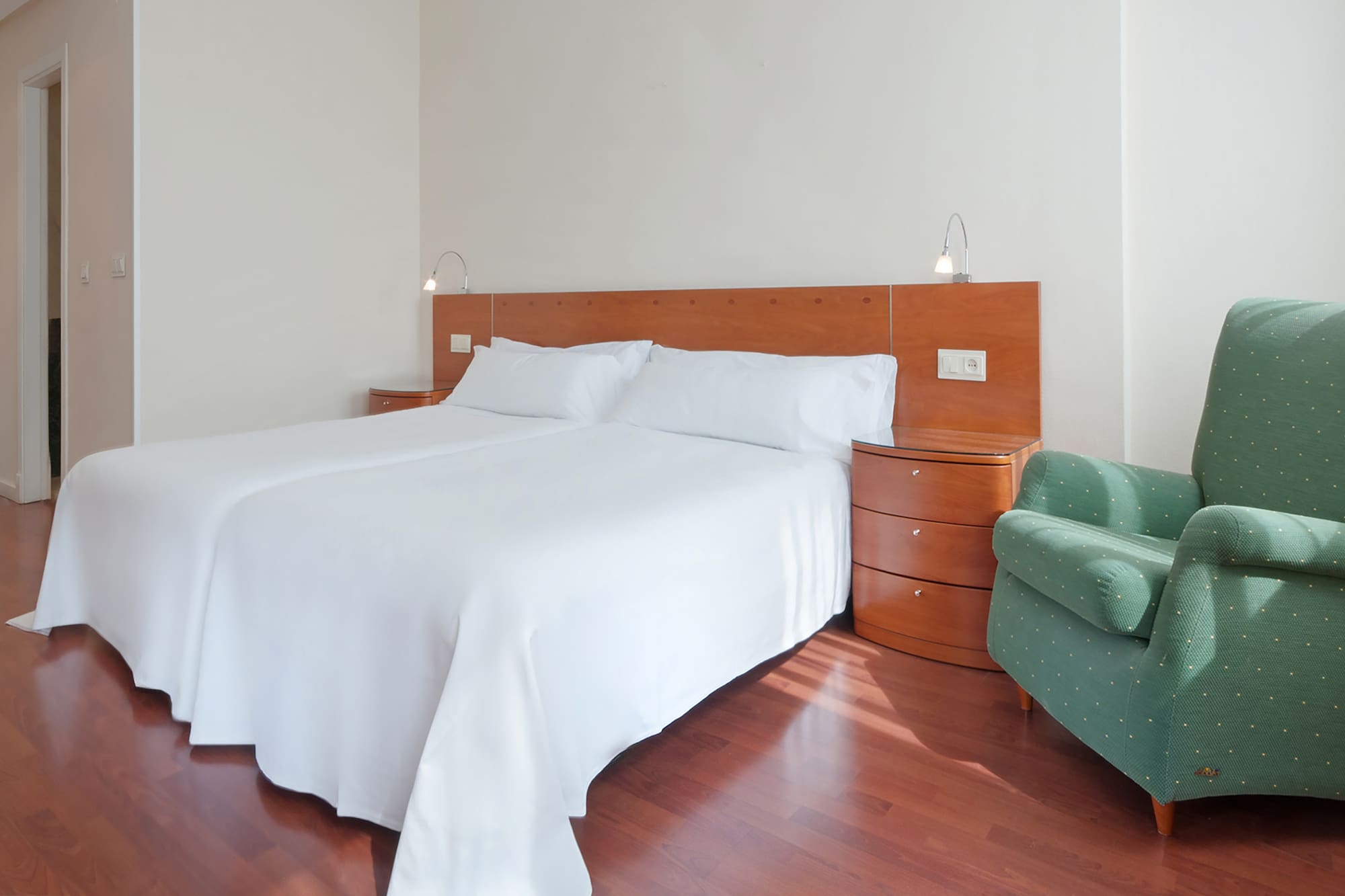 a bed with white sheets and a green chair