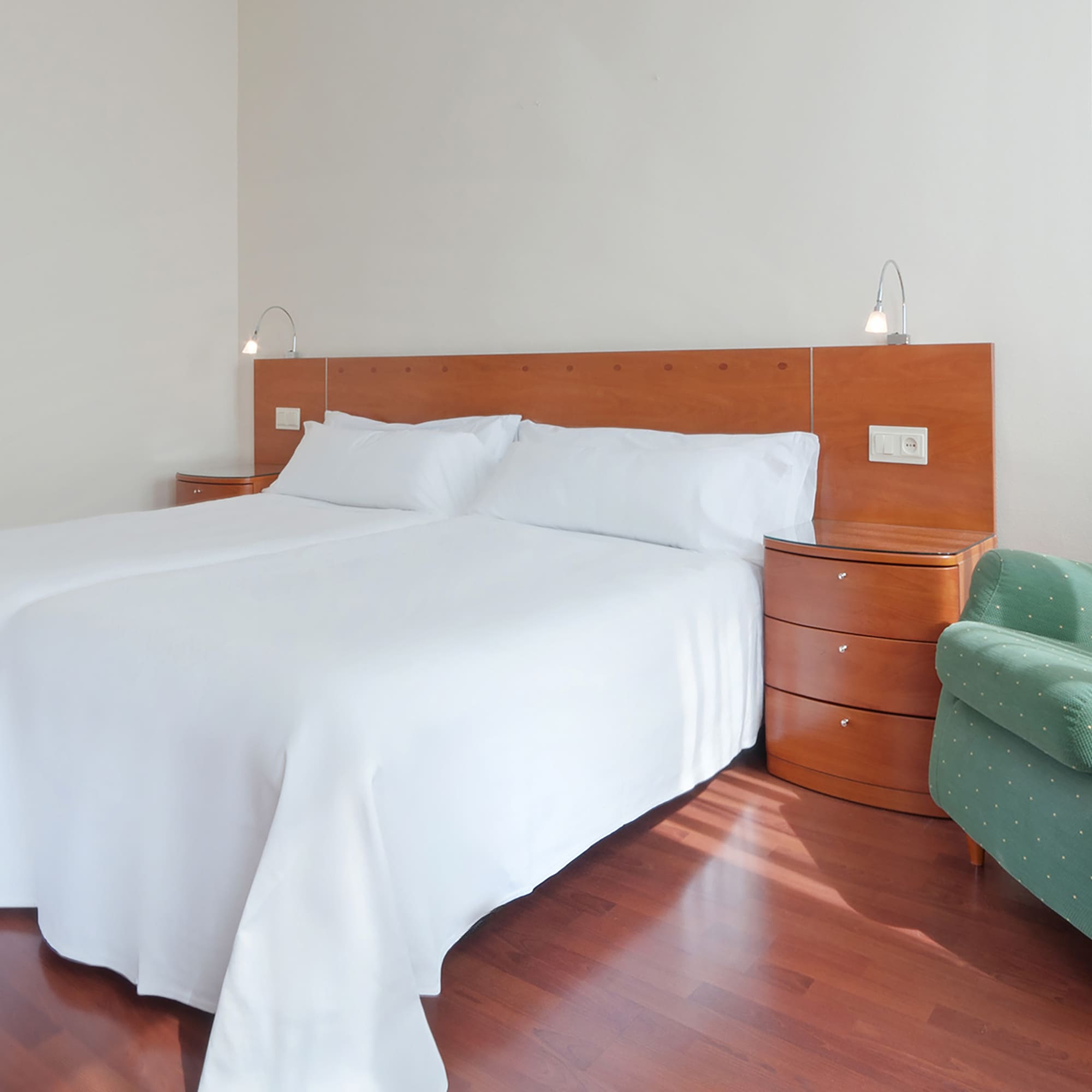 a bed with white sheets and a green chair