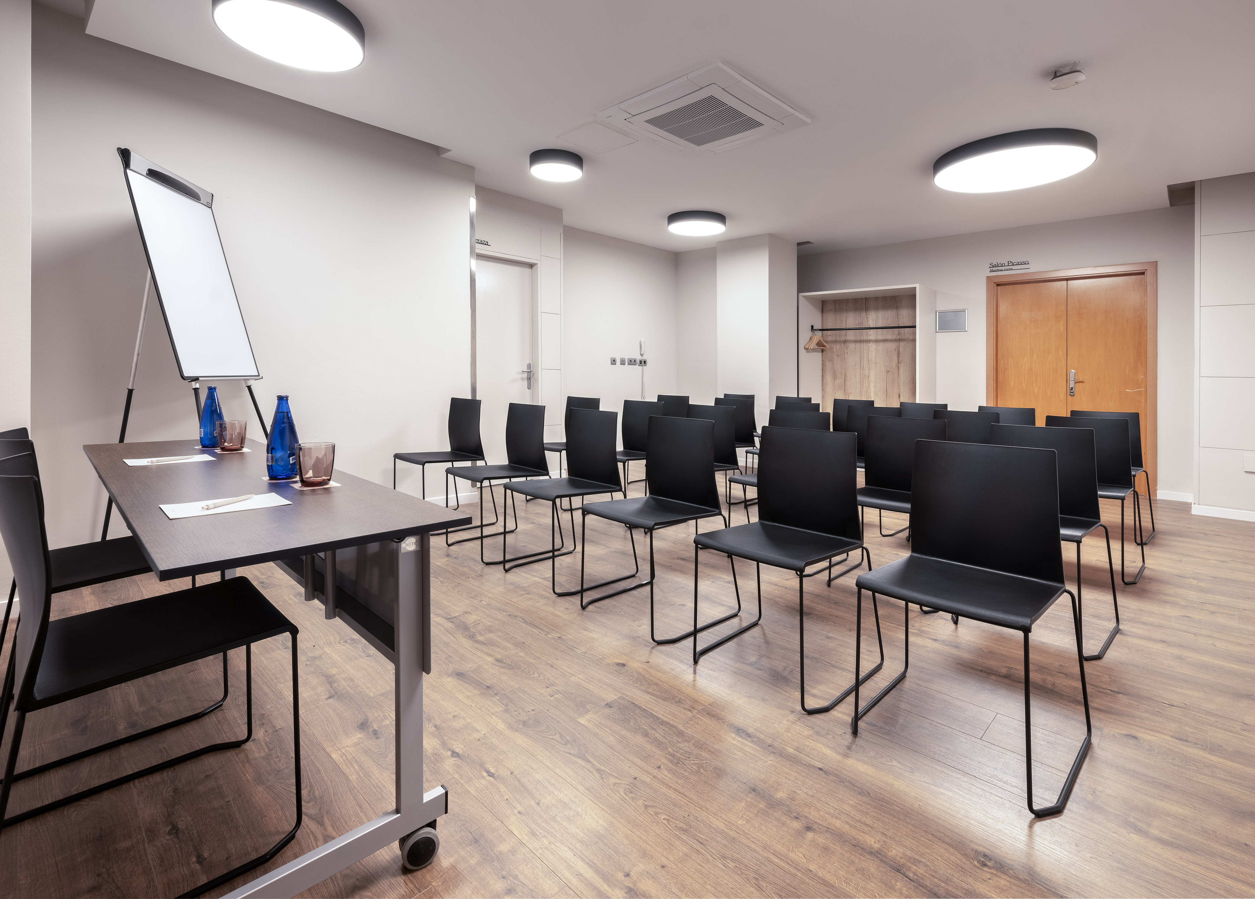 Business conference room with black chairs, flip chart, and wooden floor.