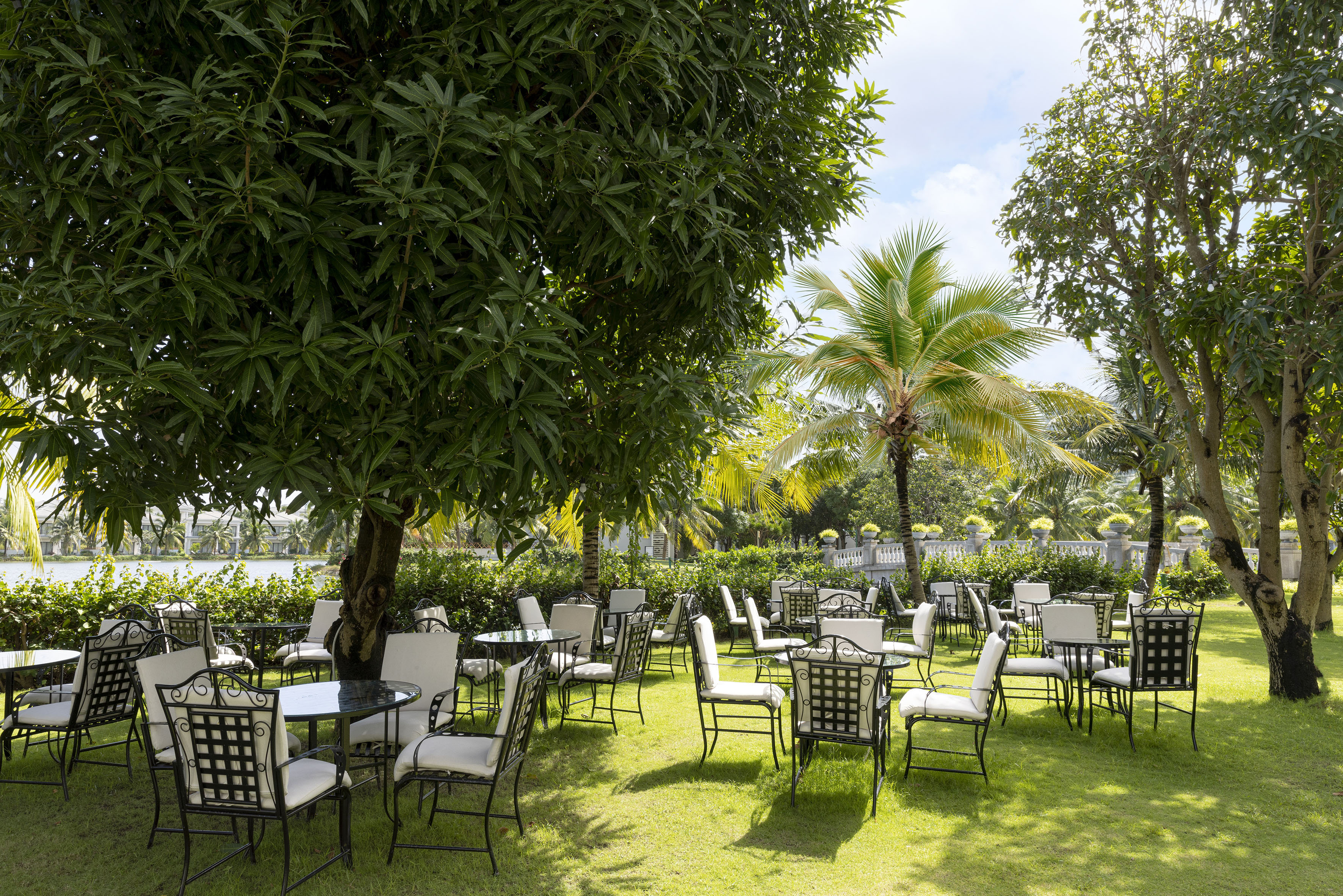 Outdoor resort dining with elegant tables, chairs in a lush tropical garden.