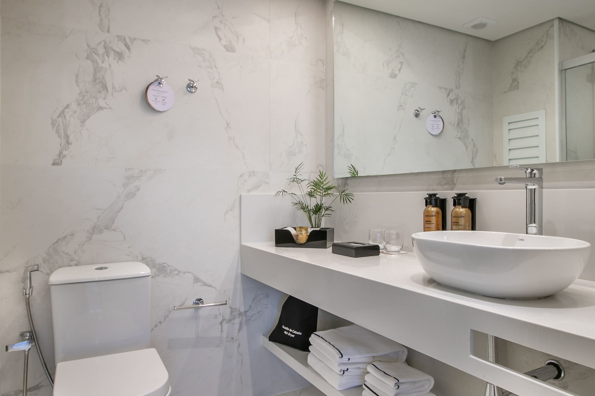 Modern white marble bathroom with sleek vanity, vessel sink, and toilet.